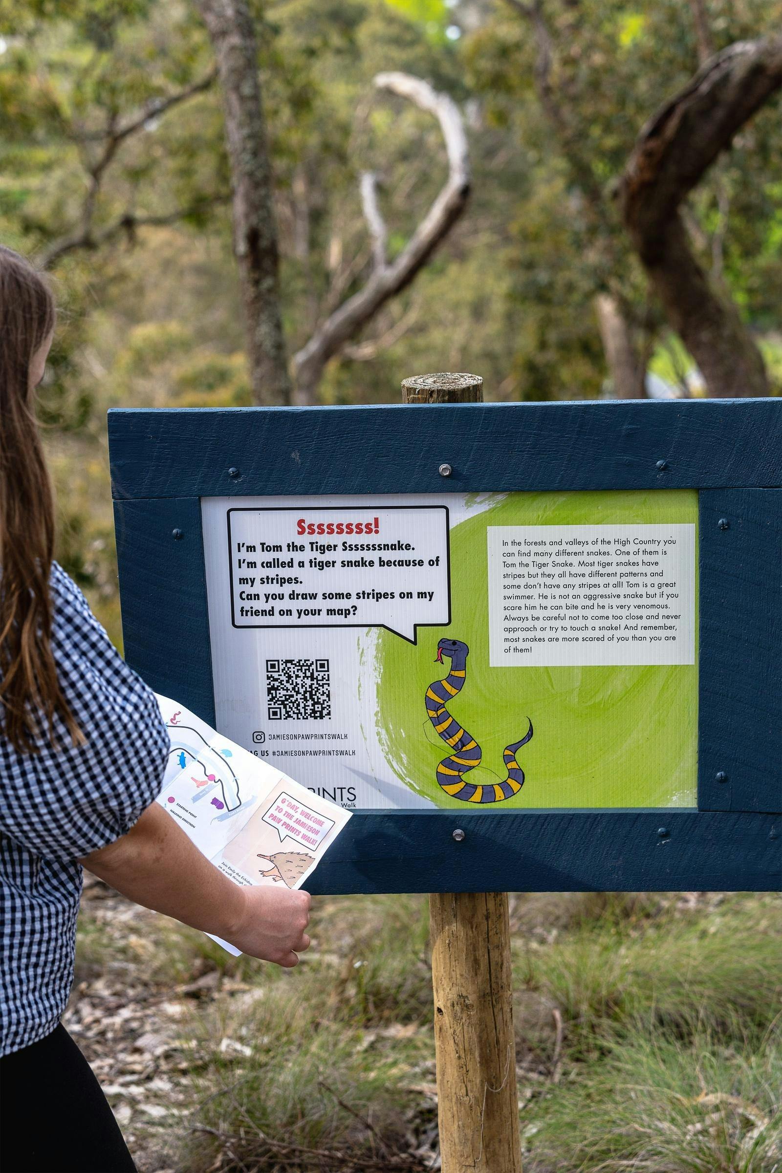 someone holding up the paw print walk pamphlet to one of the signs