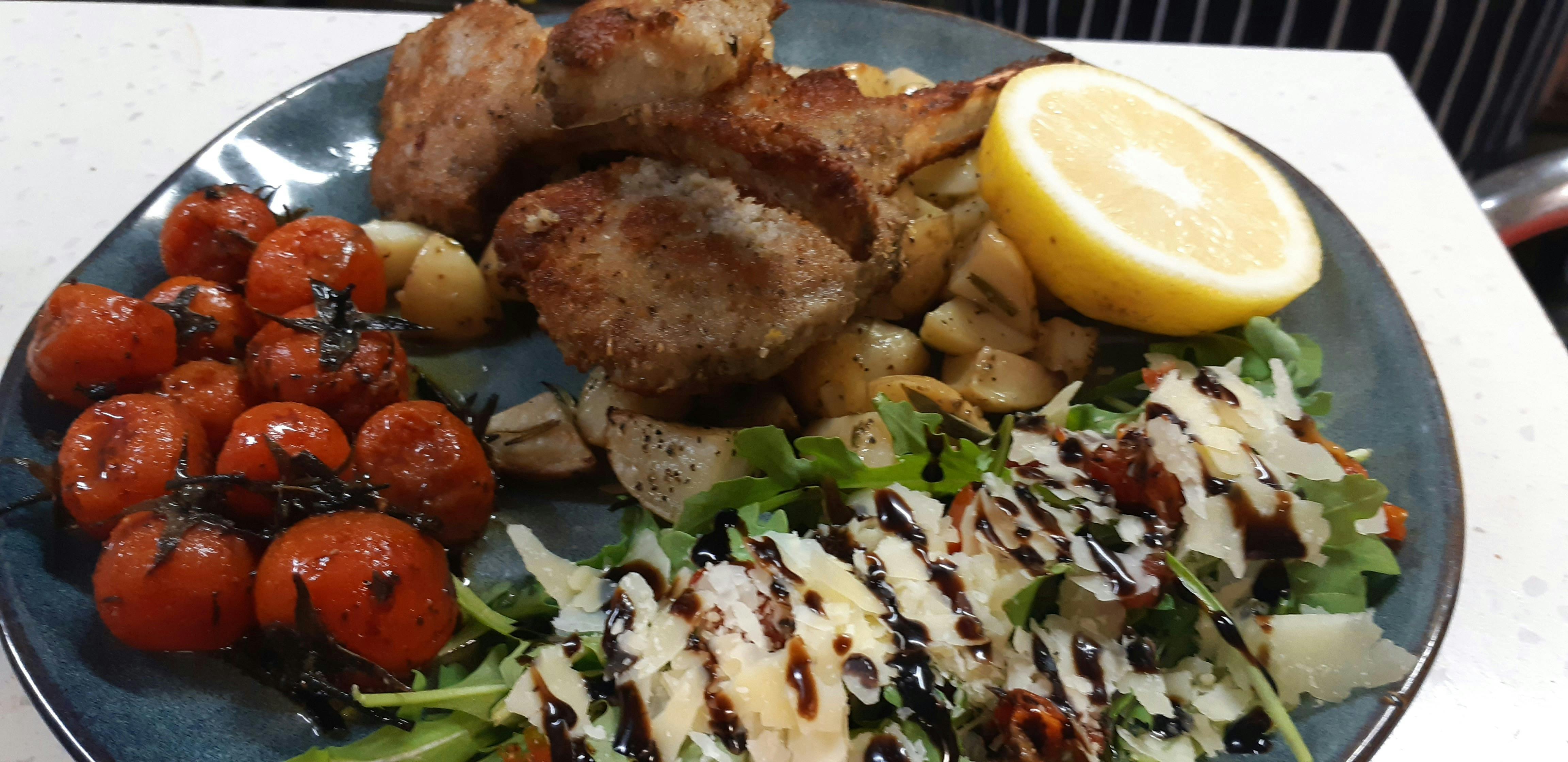 Lamb Cutlets Confit tomatoes, roast potatoes and salad on blue plateoes