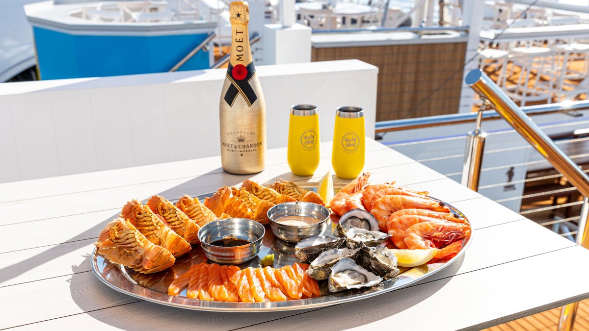 A seafood platter containing oysters, bugs, prawns and salmon sashimi with a bottle of champagne