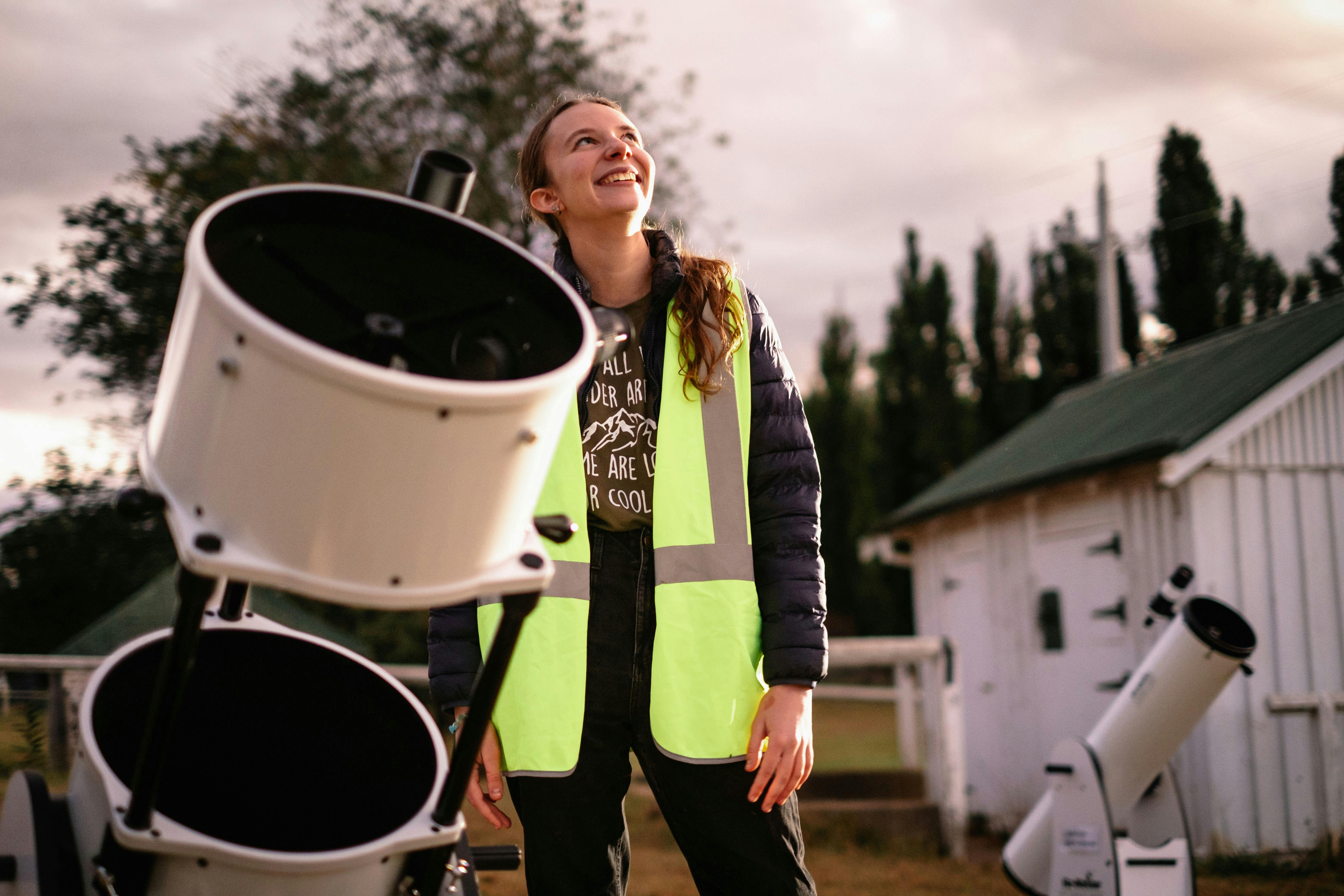 Young woman standing next to telescope looking towards the sky at Lanyon Homestead