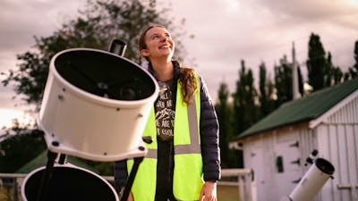 Young woman standing next to telescope looking towards the sky at Lanyon Homestead