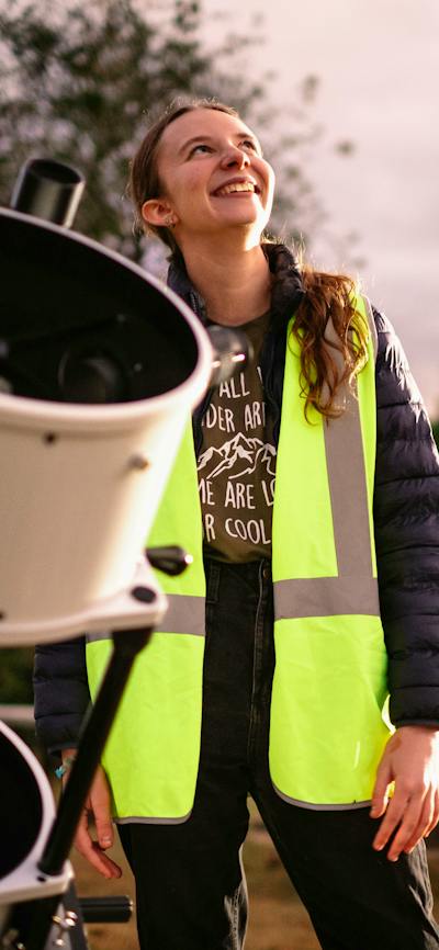 Young woman standing next to telescope looking towards the sky at Lanyon Homestead