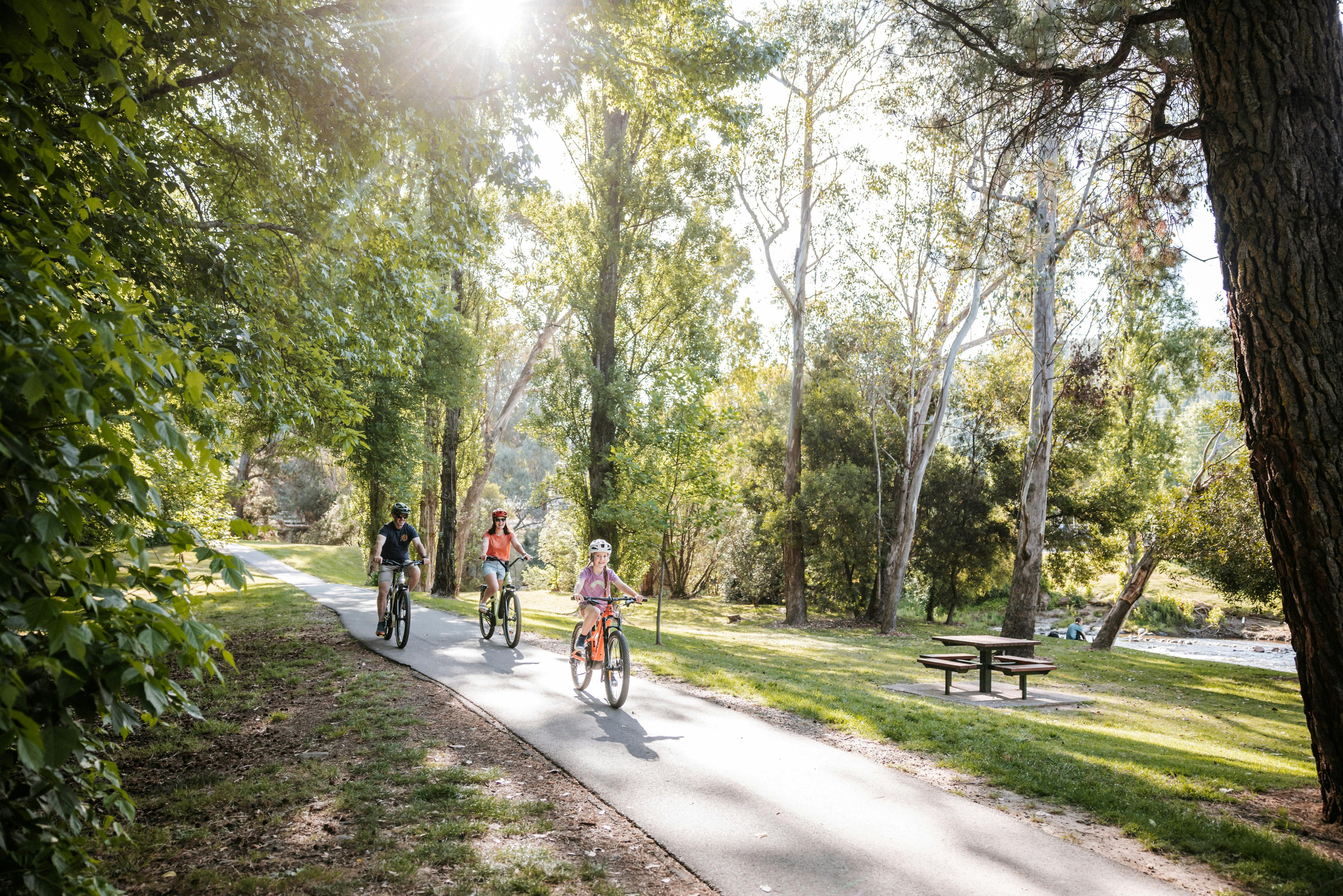 Stylish riding in the Alpine region of Bright victoria, family enjoying riding hire bikes next to a