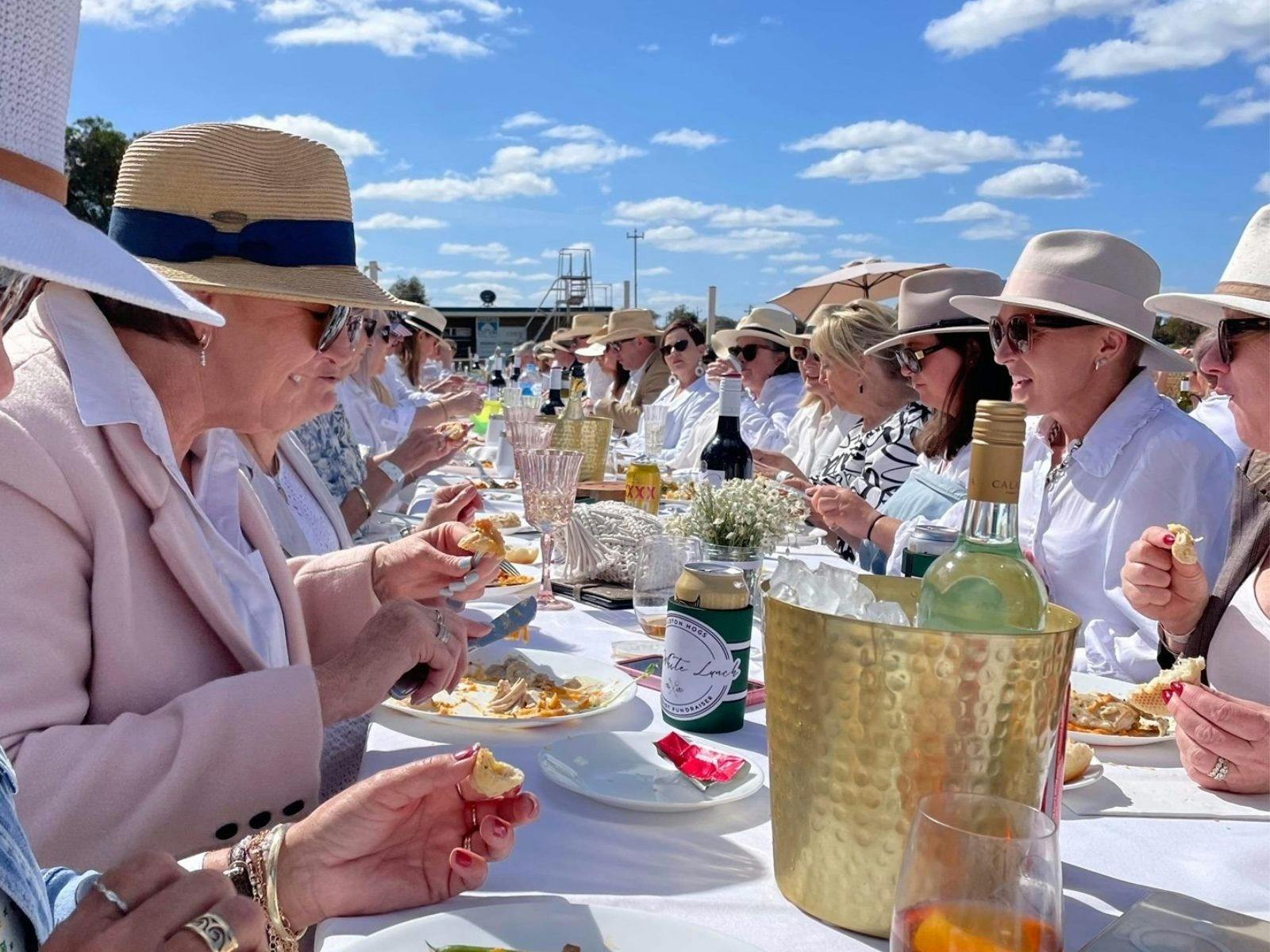 People wearing white eating at a long table