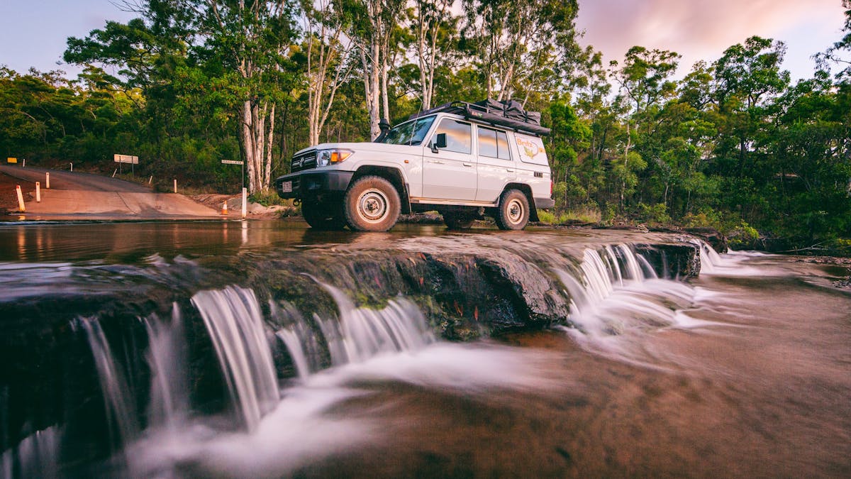 4WD hire car parked in flowing creek water at top of Isabelle Falls.