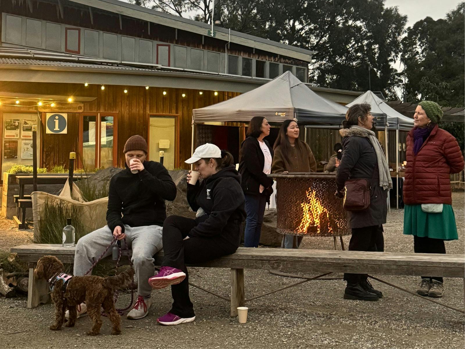 People sit around the fire with their dog on a leash