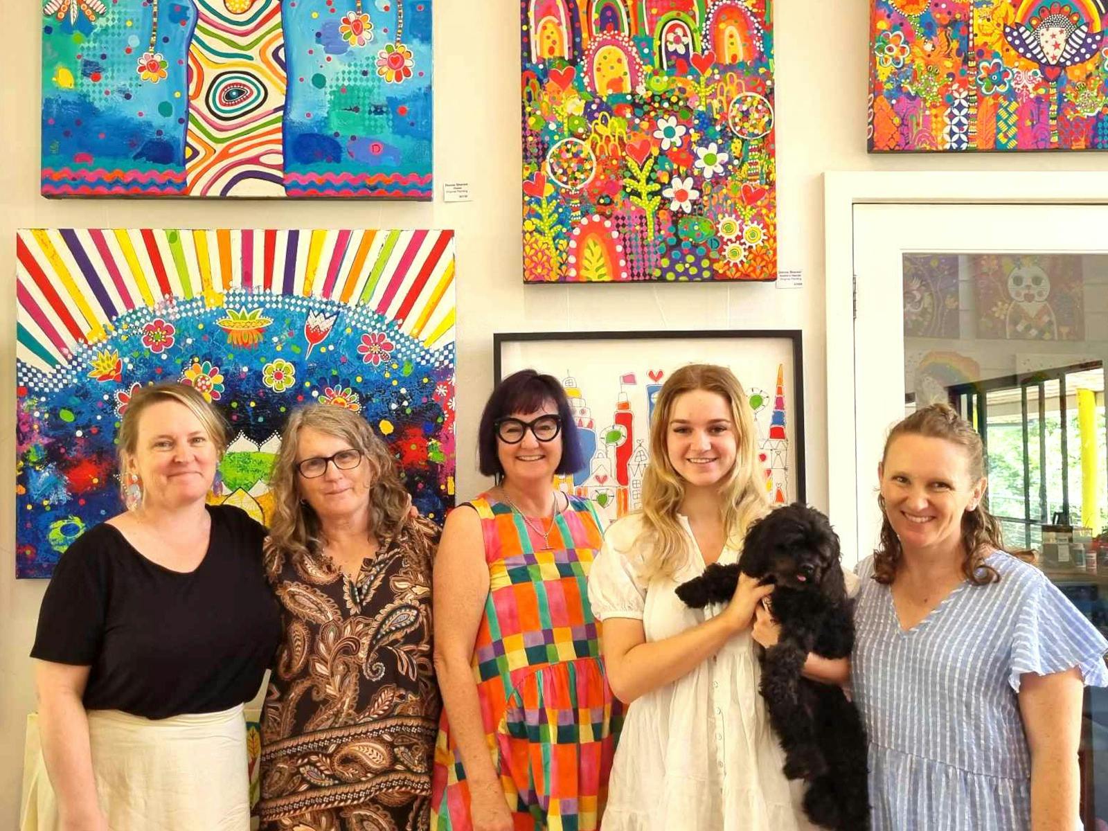 Ladies on a tour of Donna Sharam's studio. smiling in front of bright paintings