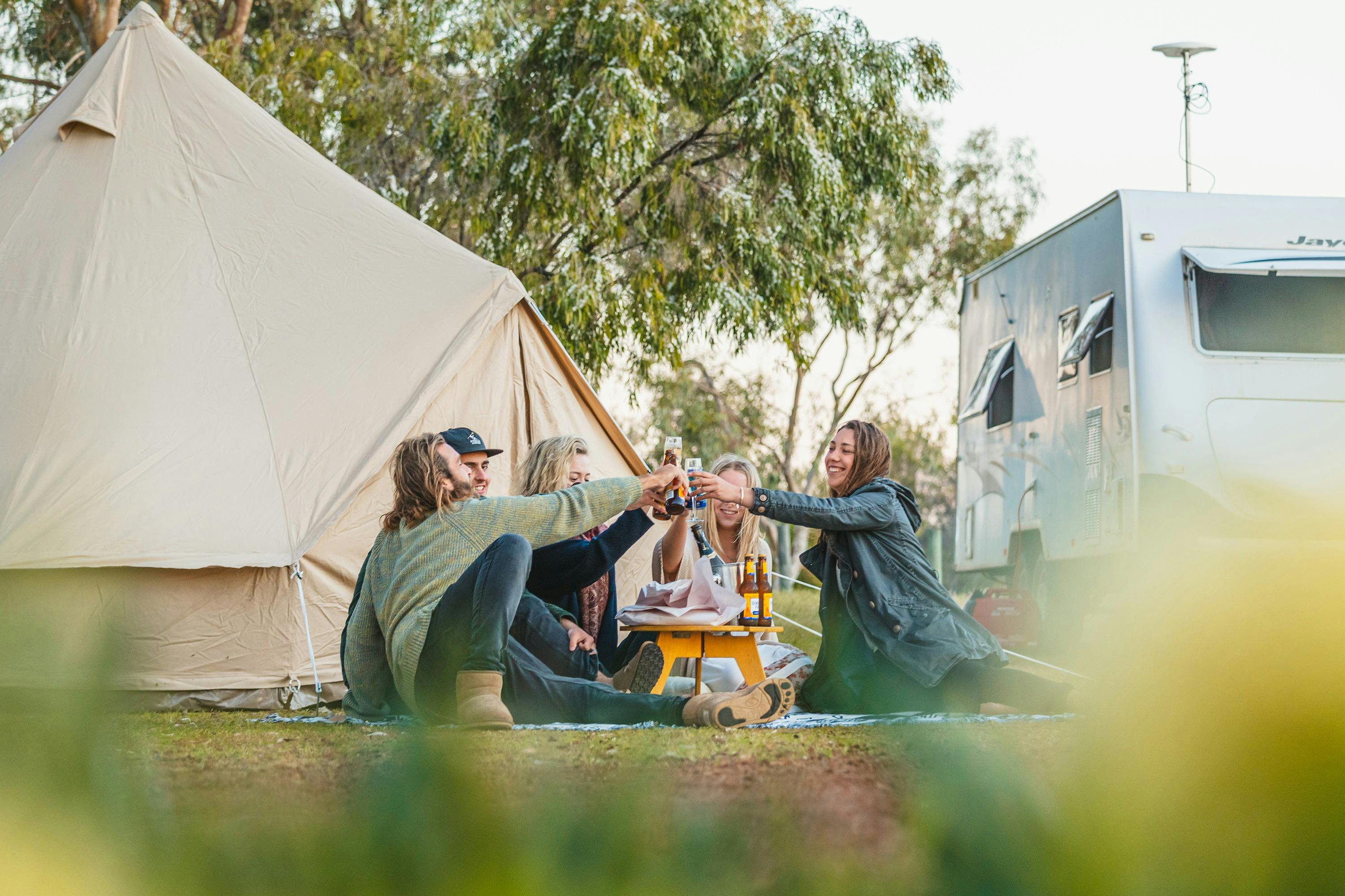 A ground of friends sitting in front of a tent and caravan at Herron Point Campground