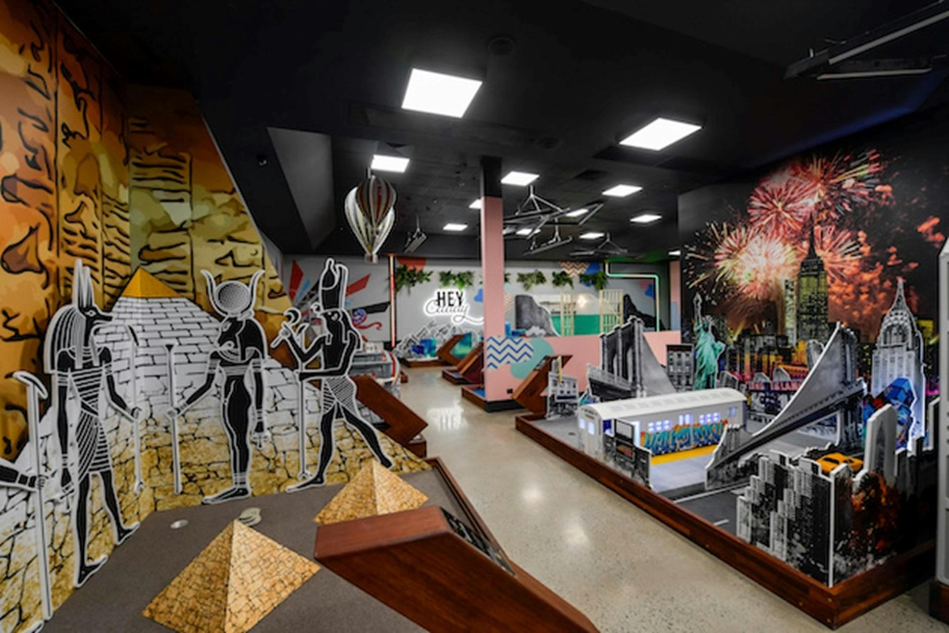 a room with a themed mini-golf course, includes pyrimids and a New York streetscape.
