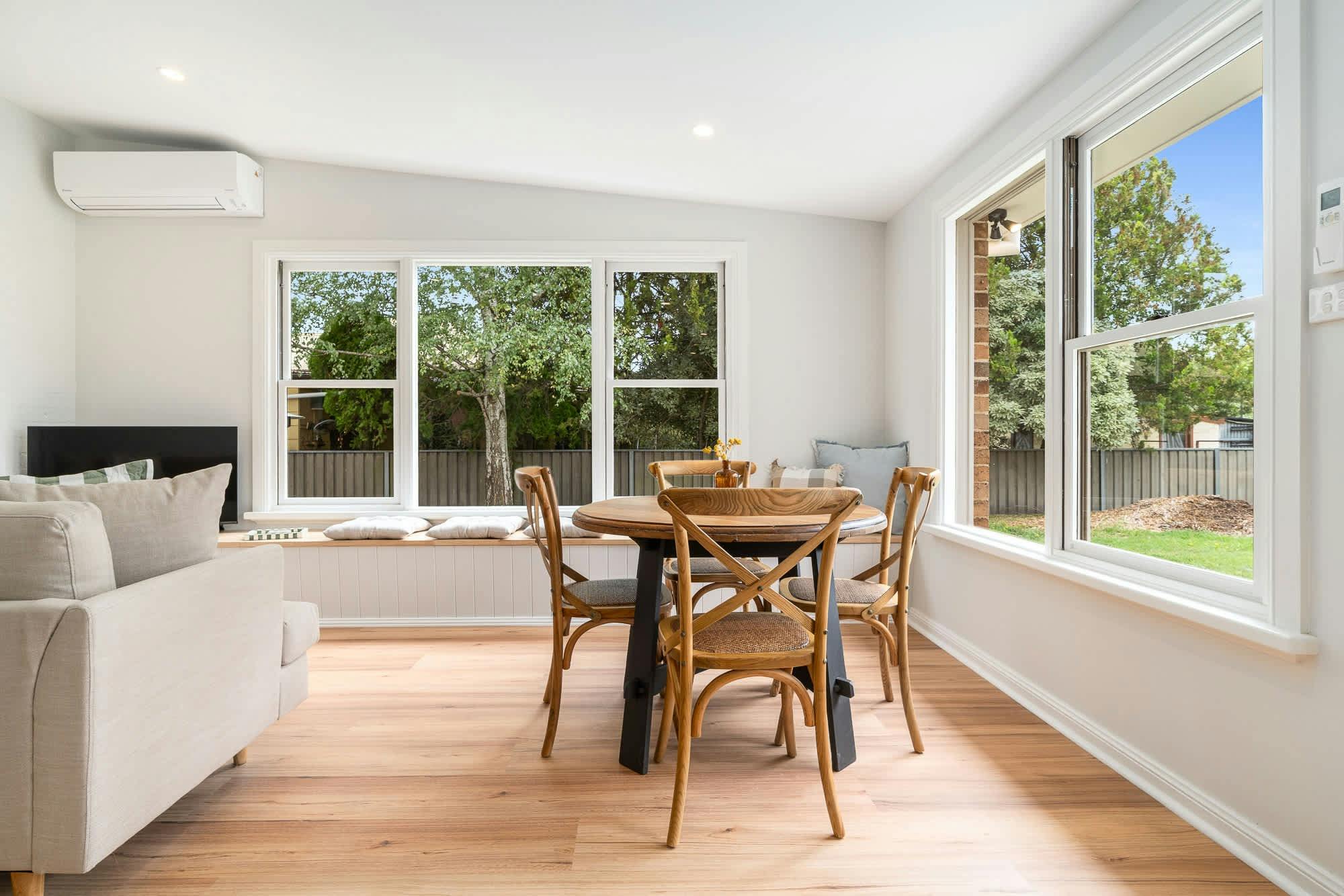 4 seater dining table with 2 large windows looking out to the backyard. In the main living area.