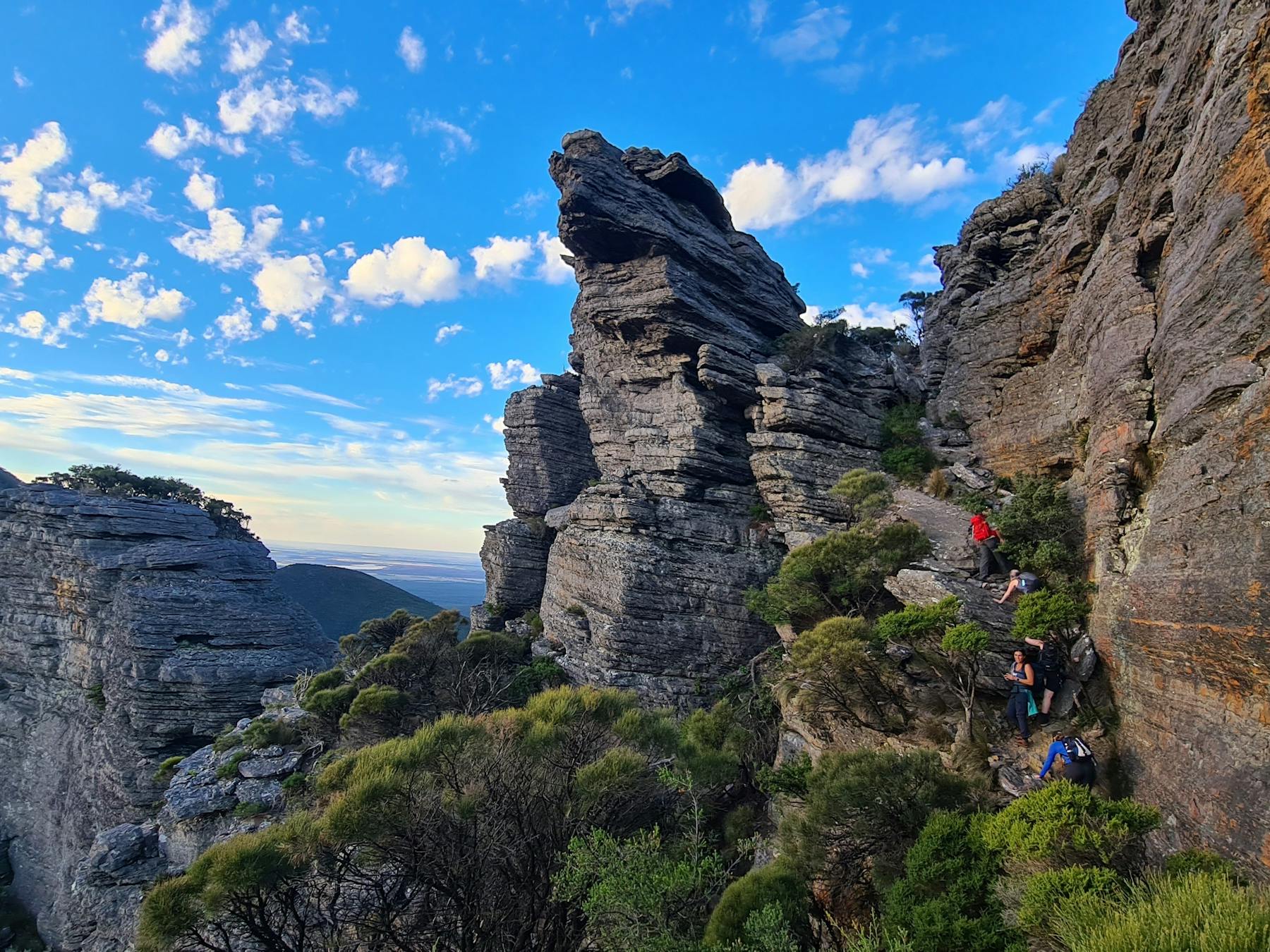 Giant mountain peak with hikers scaling the rock face