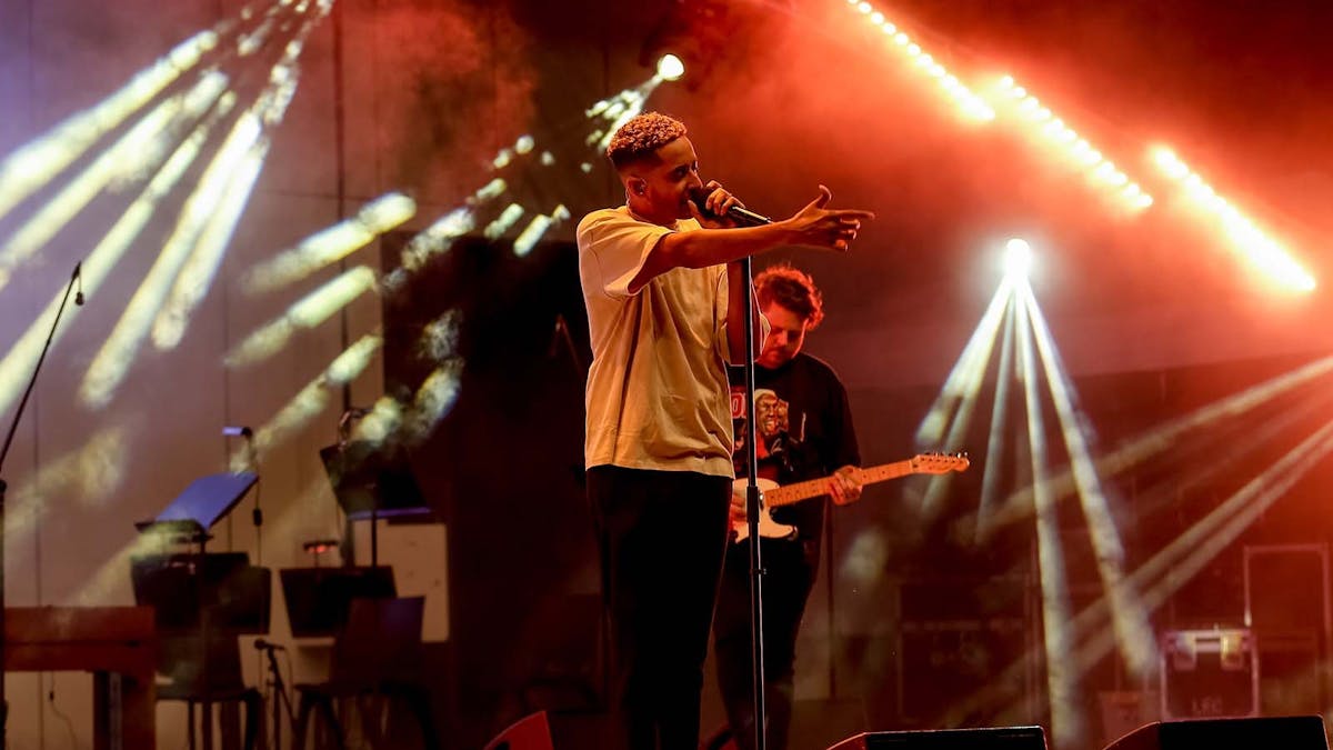 Man on stage singing with band member behind. Man on stage singing with band member behind.