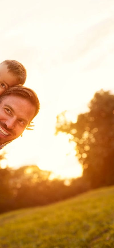 Child smiling on father’s back