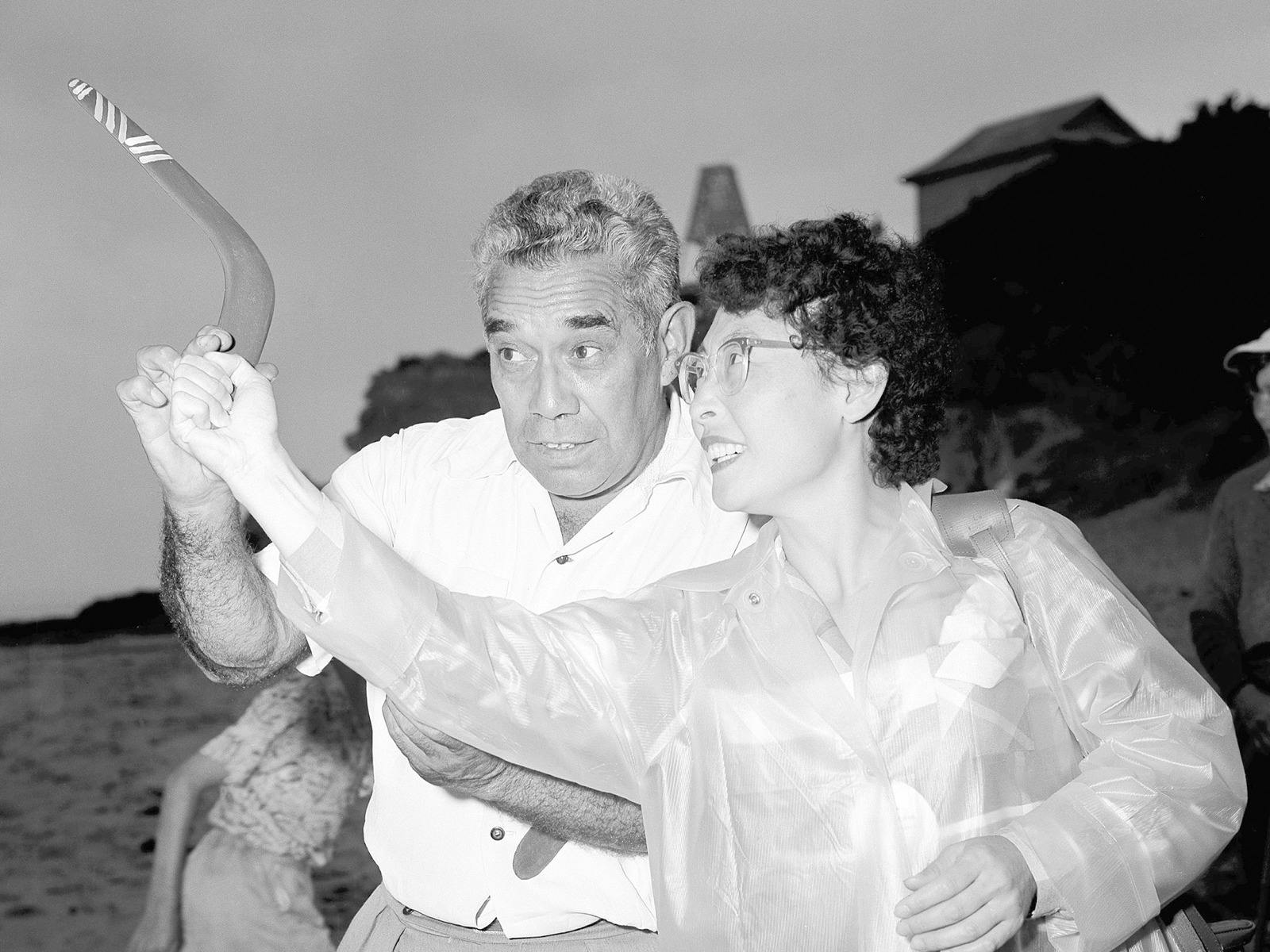 A man teaches women how to throw a boomerang in 1957.