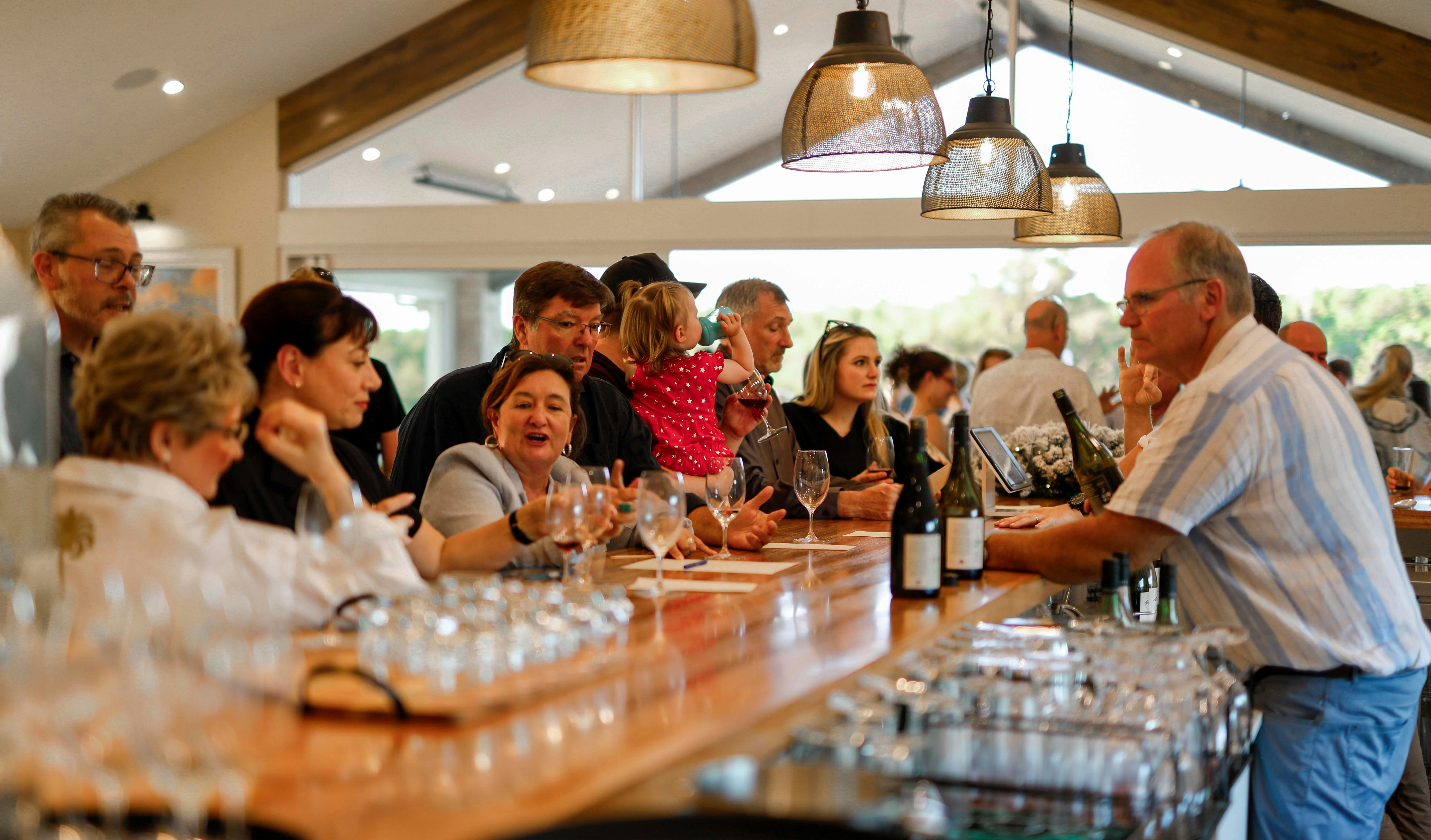 People gathered around a bar for a wine tasting.
