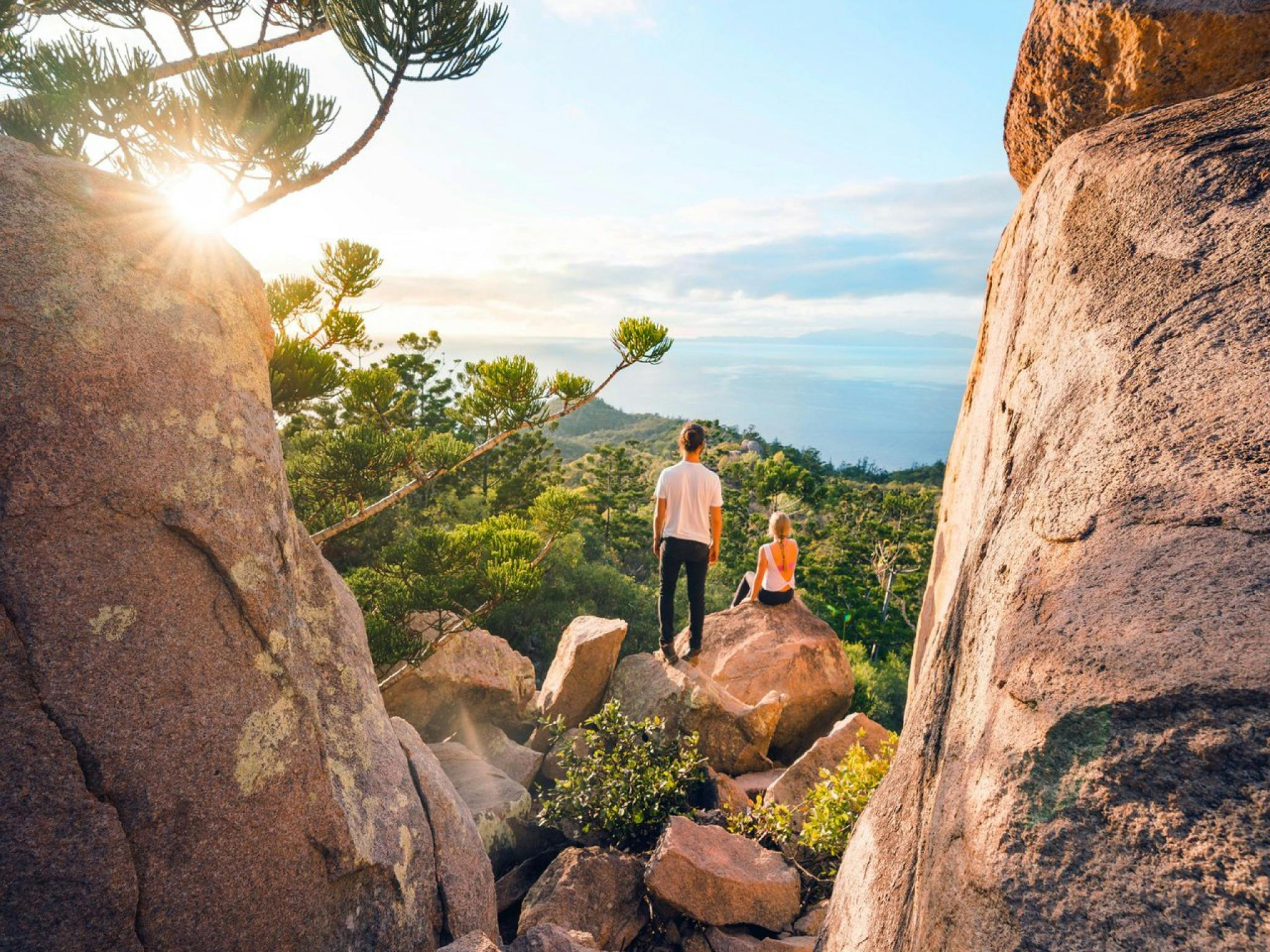 Two people sitting on a rock on a cliff face Two people sitting on a rock on a cliff face