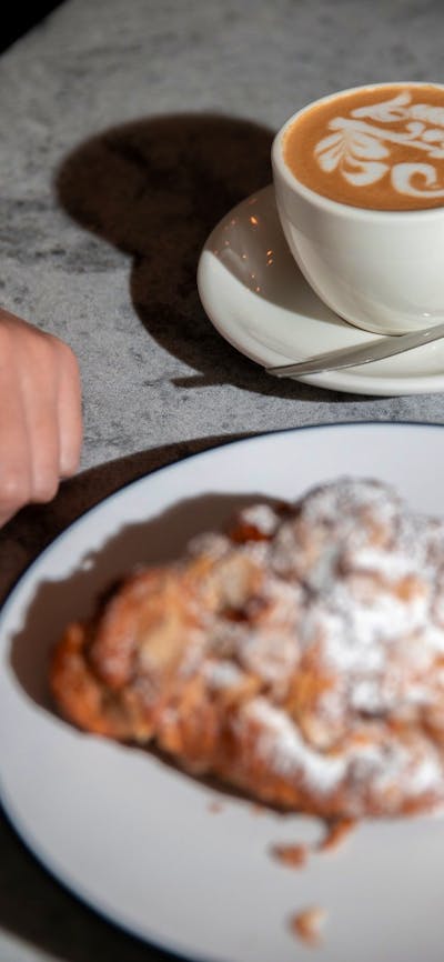 Cup of coffee and plate of pastry on table