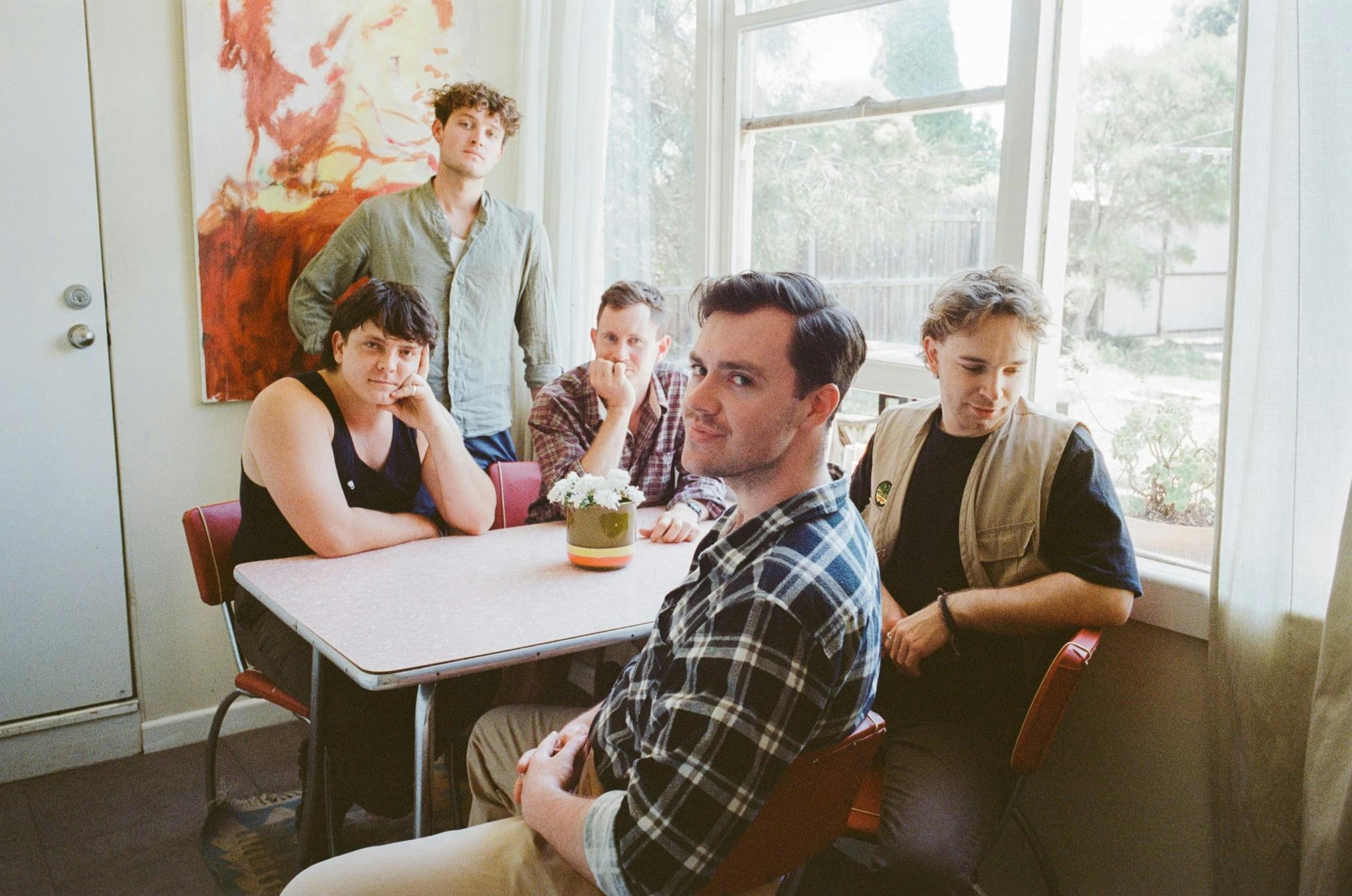 five band members sit around the kitchen table