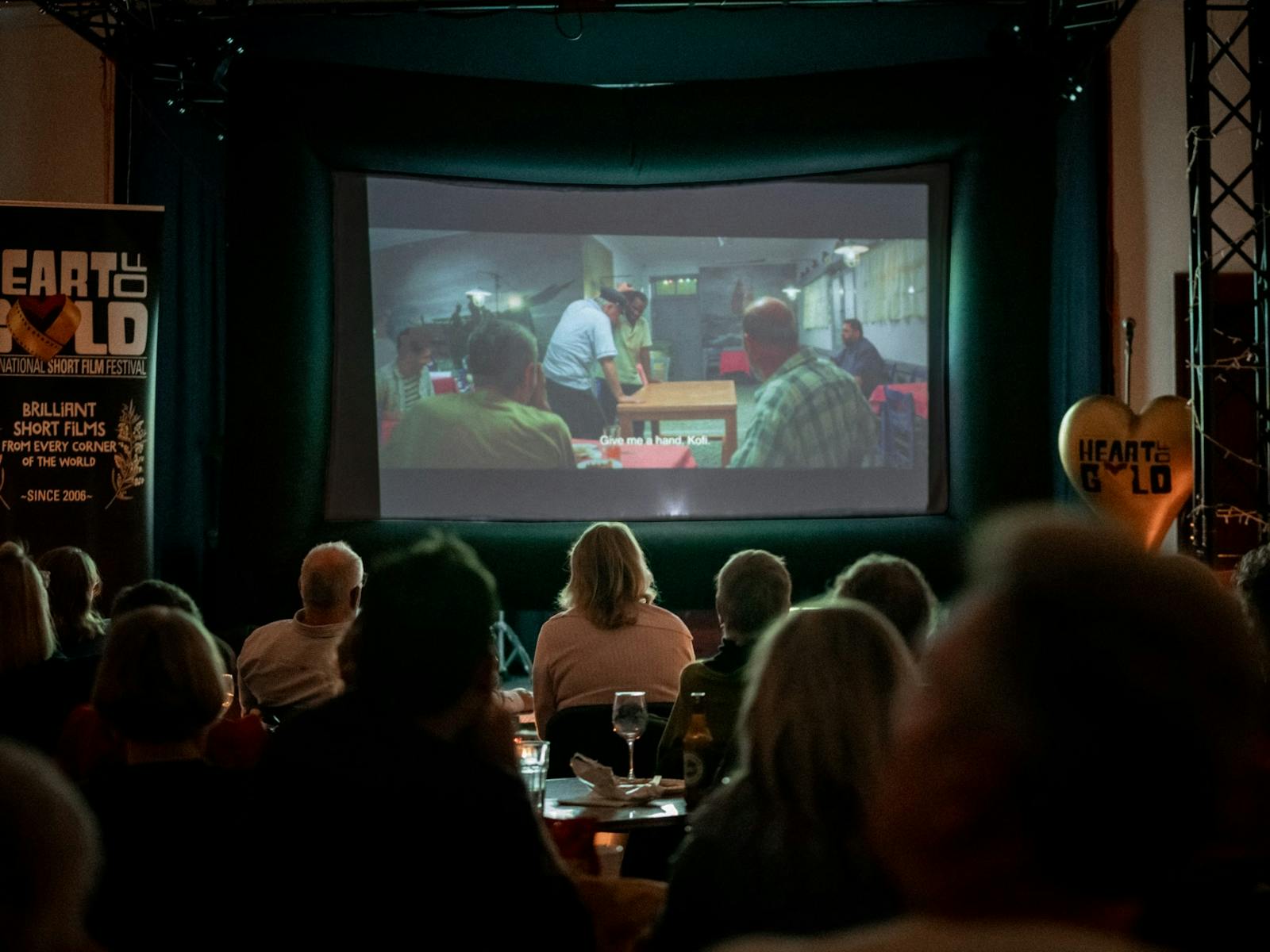 Darkened cinema with film showing and siloettes of audience Darkened cinema with film showing and siloettes of audience