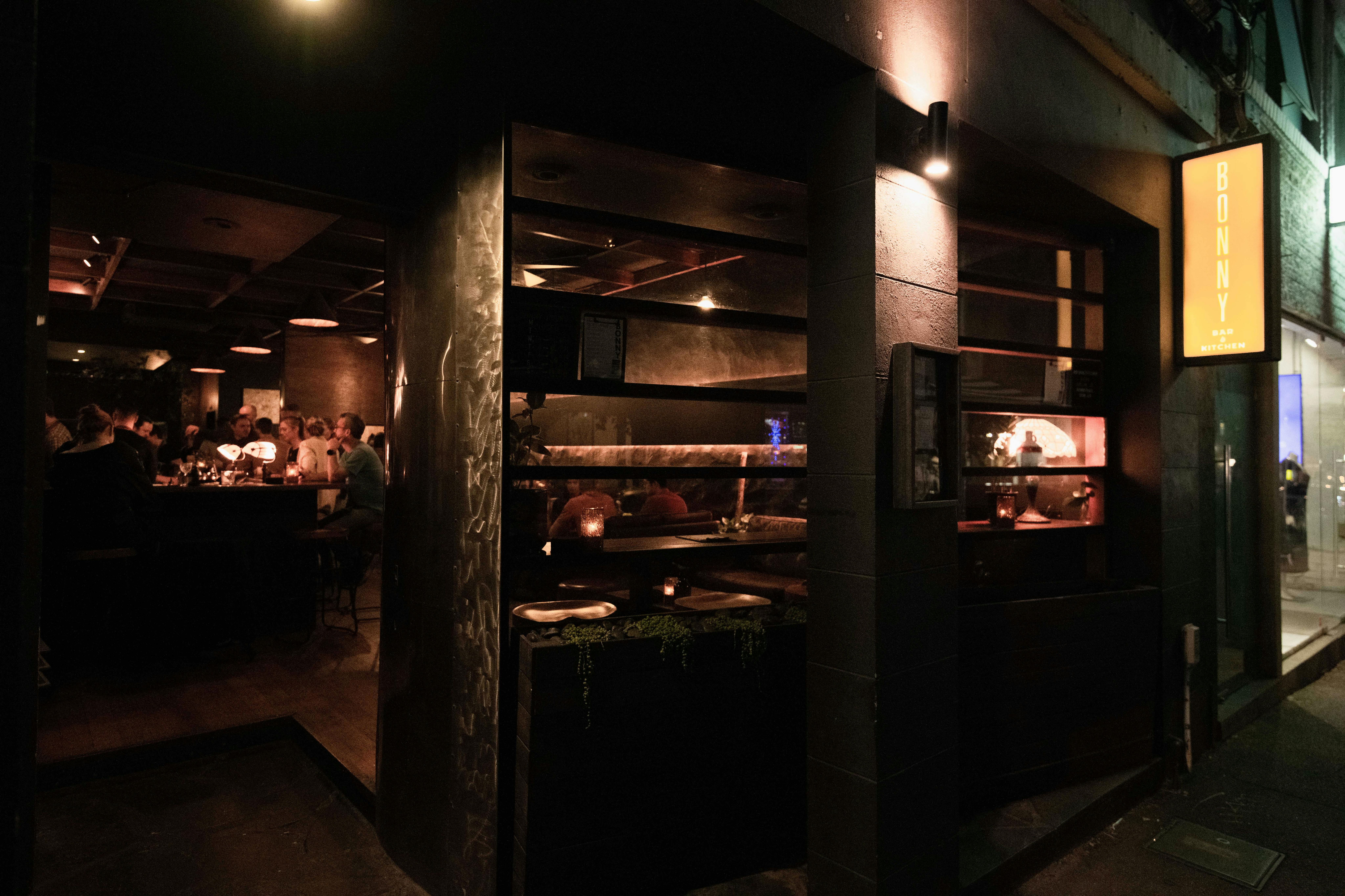 The exterior of a bar from the footpath at the entrace showing the window into the bar.