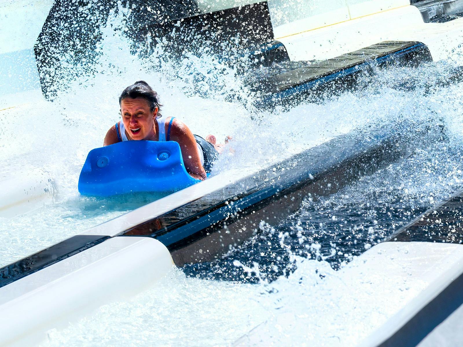 Woman zooming past head first on the Kraken Racer waterslide. Kraken has black & white stripes
