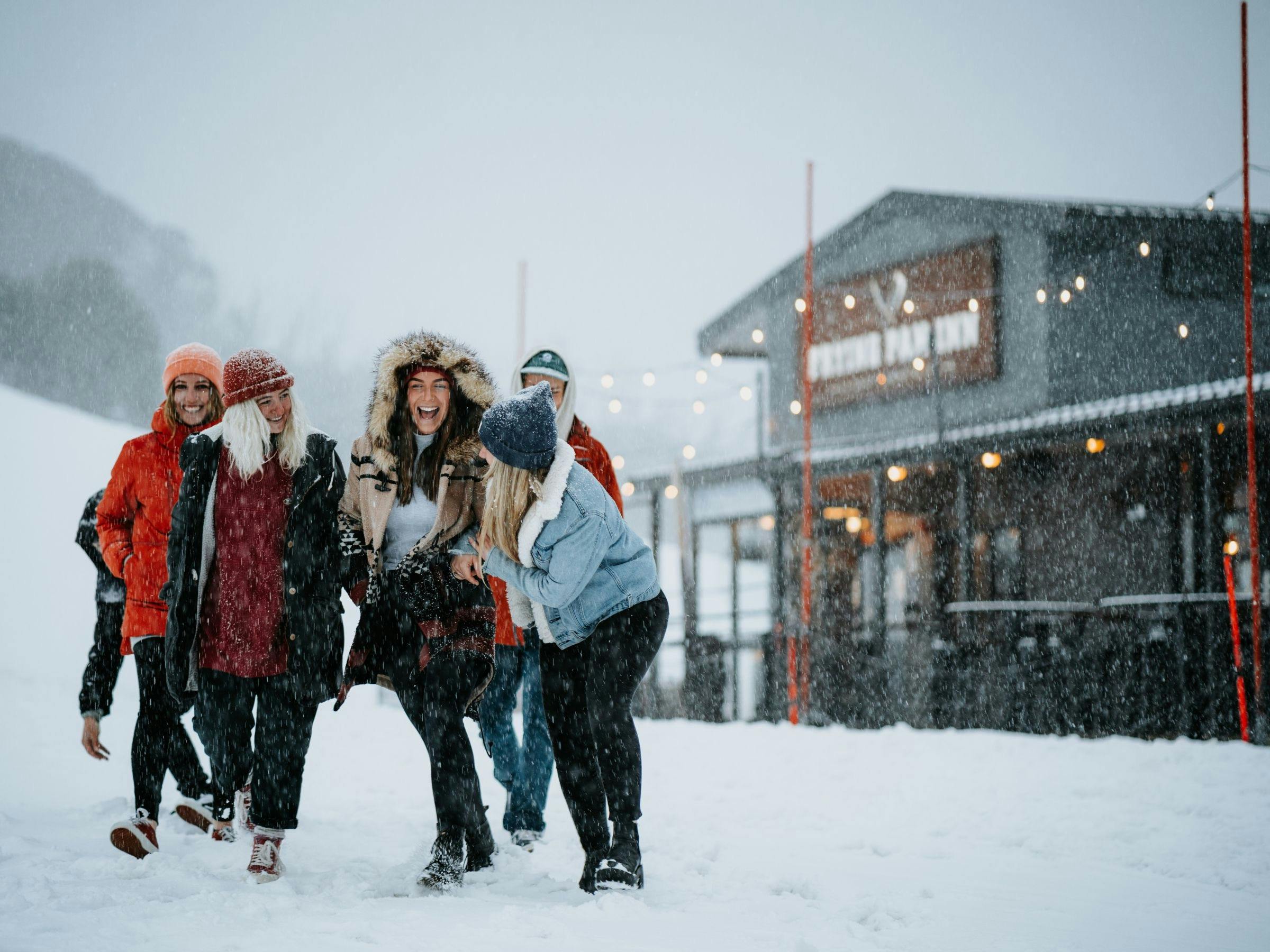An image of friends gathering at the front of Frying Pan Inn while it snows