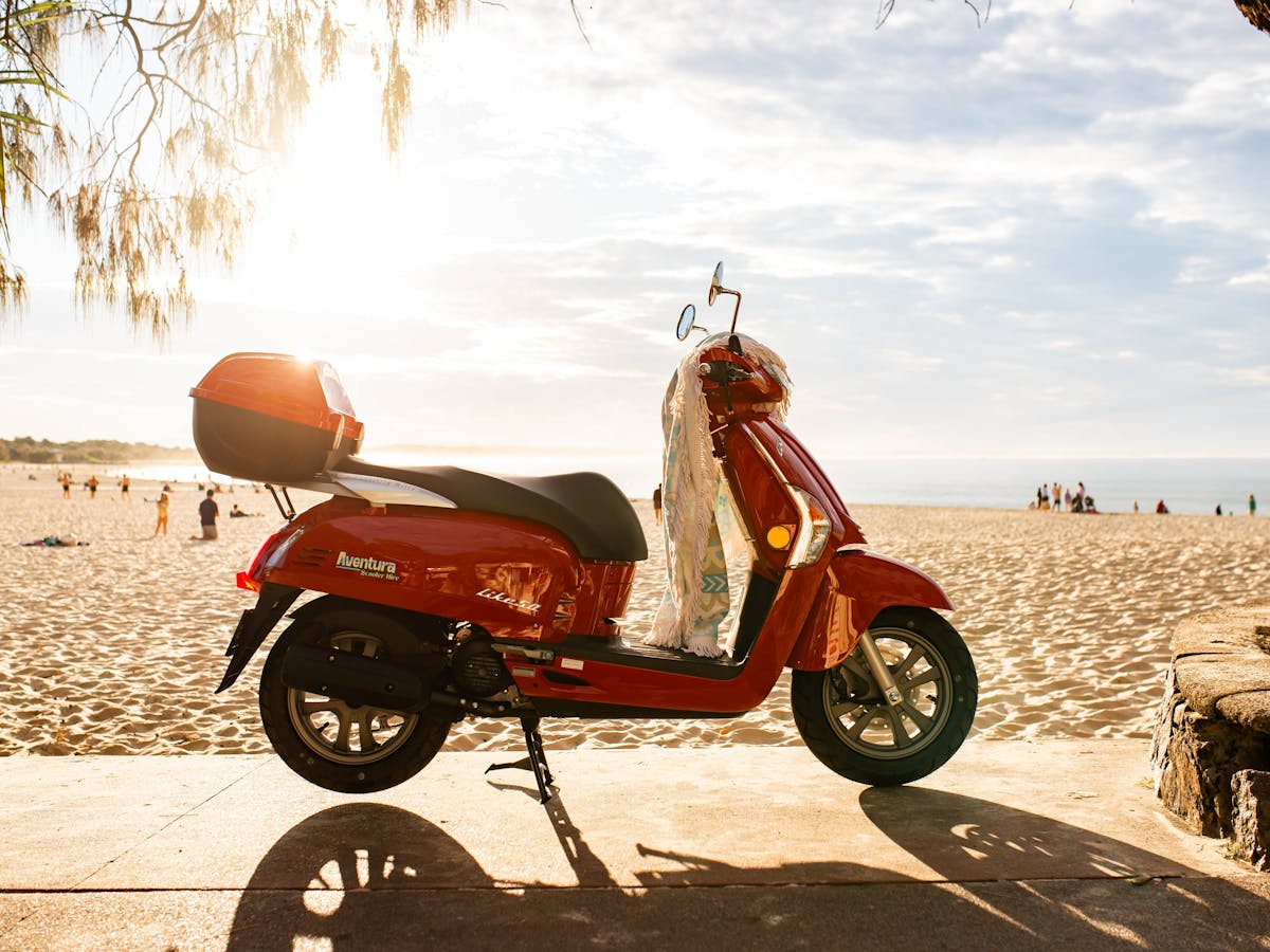 photo of red scooter with towel draped over handle bars at Noosa Main Beach at sunset