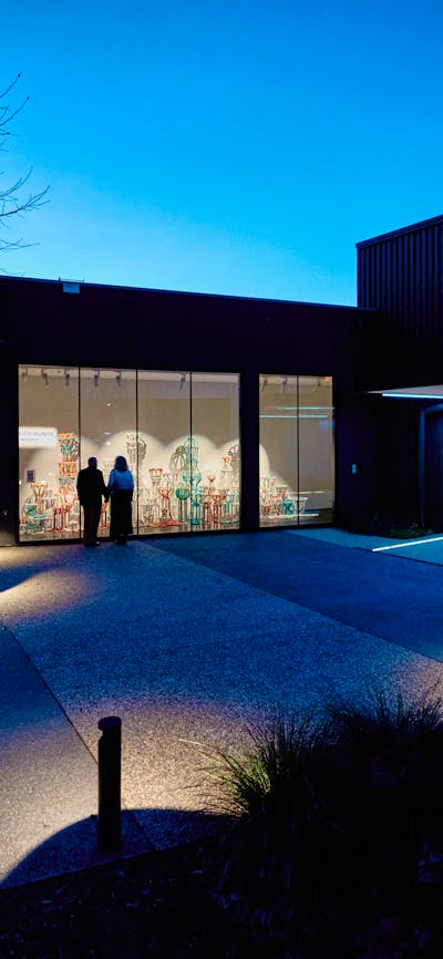 A couple look at the window gallery at the entrance of the Belco Arts Theatre on a clear night.