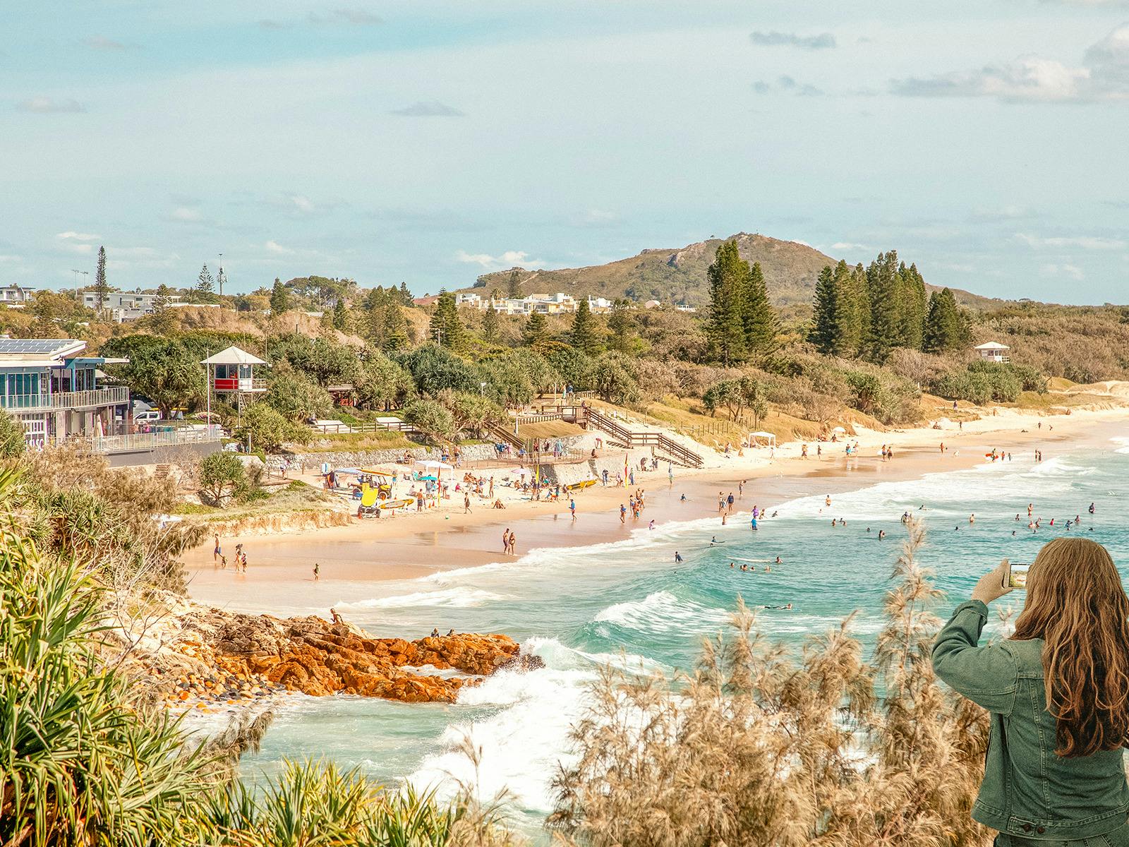 High angle of Coolum Beach looking north to Emu Mountain with girl taking a photo from a smartphone High angle of Coolum Beach looking north to Emu Mountain with girl taking a photo from a smartphone