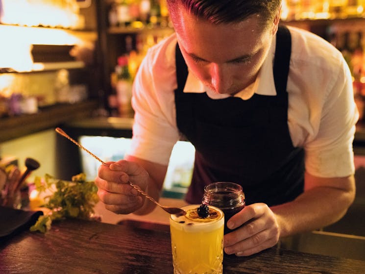 Bartender creating a cocktail at The Doss House bar in The Rocks