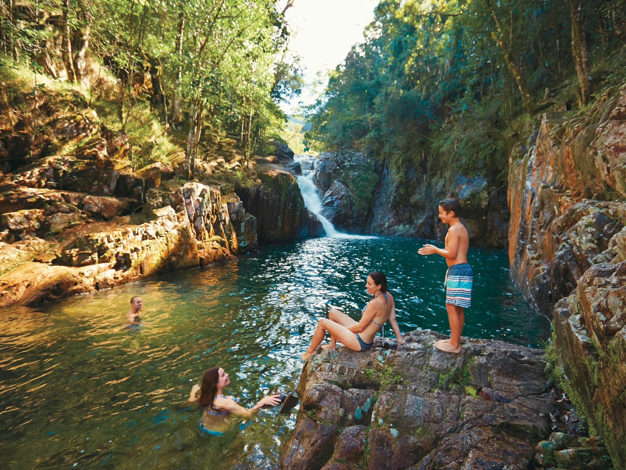 family swimming by waterfall family swimming by waterfall