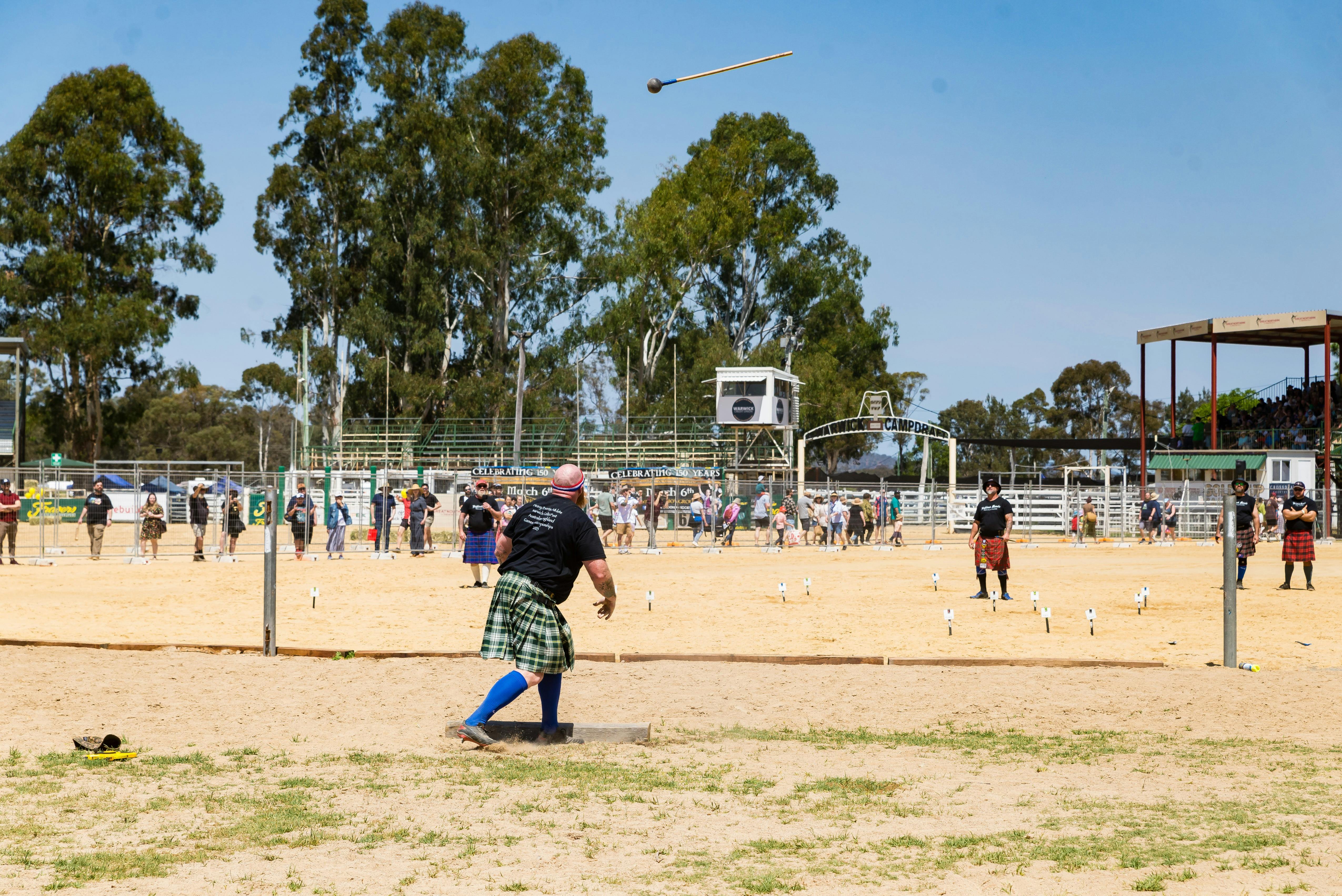 A strongman watches the hammer he has just thrown flying through the air