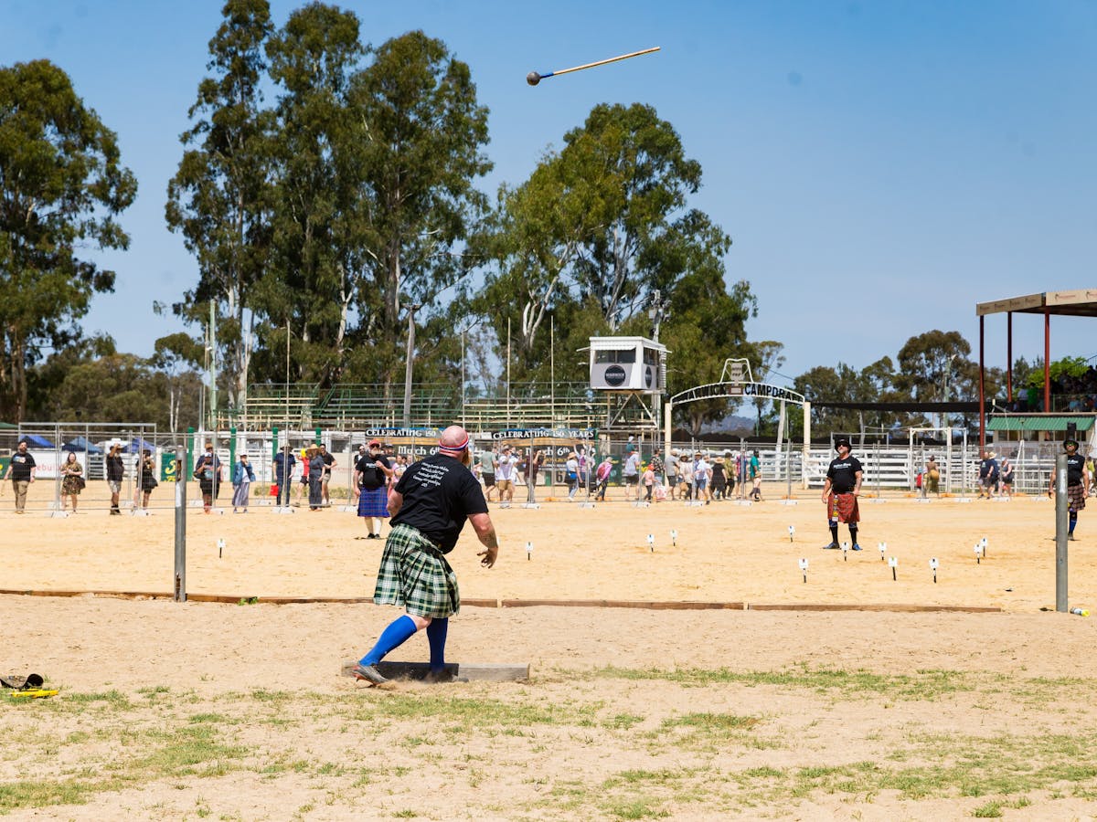 A strongman watches the hammer he has just thrown flying through the air
