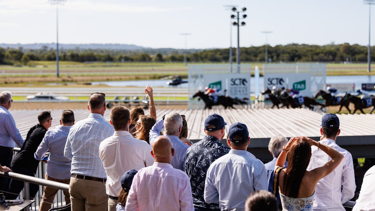 People watching and cheering on the thoroughbred horses crossing the finishing post