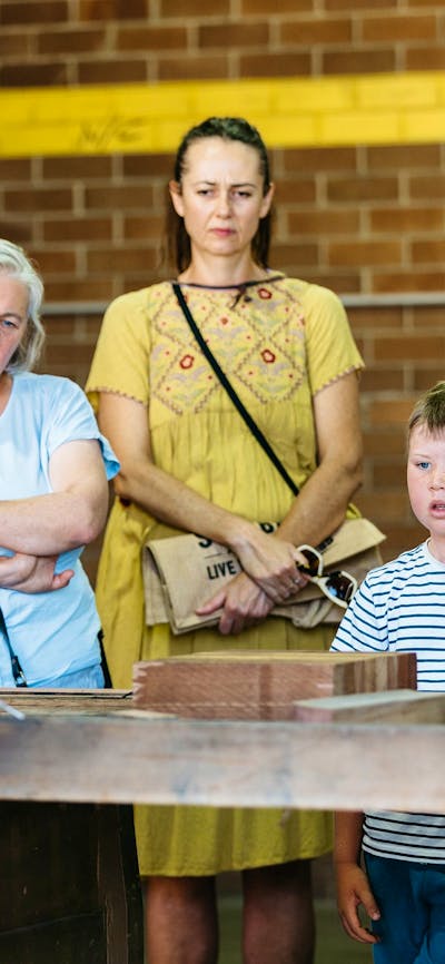 Visitors of all ages enjoying a demonstration by skilled craftsman and staff member