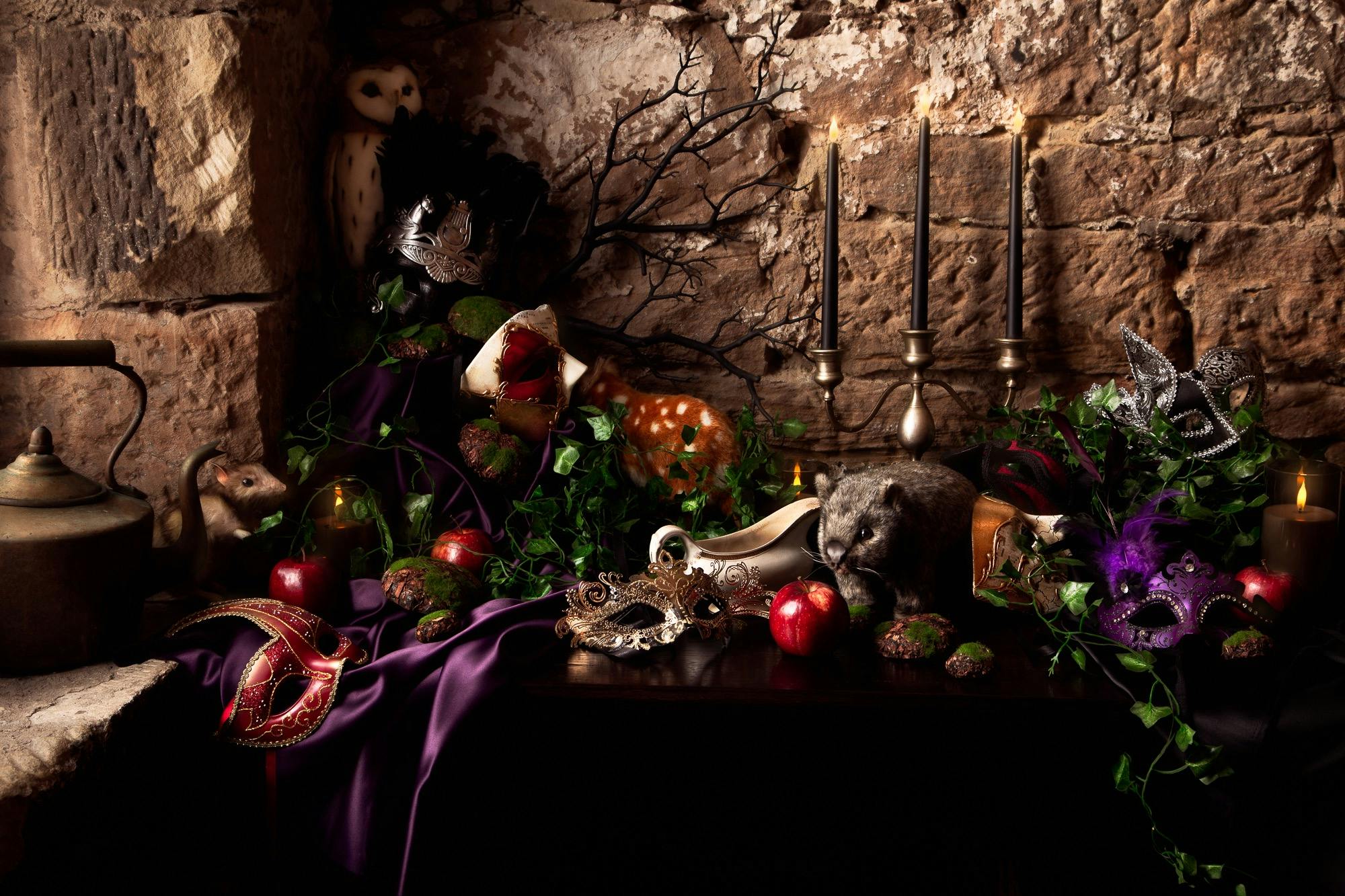 An opulent table setting decorated with apples, masks a candelabra and native animals
