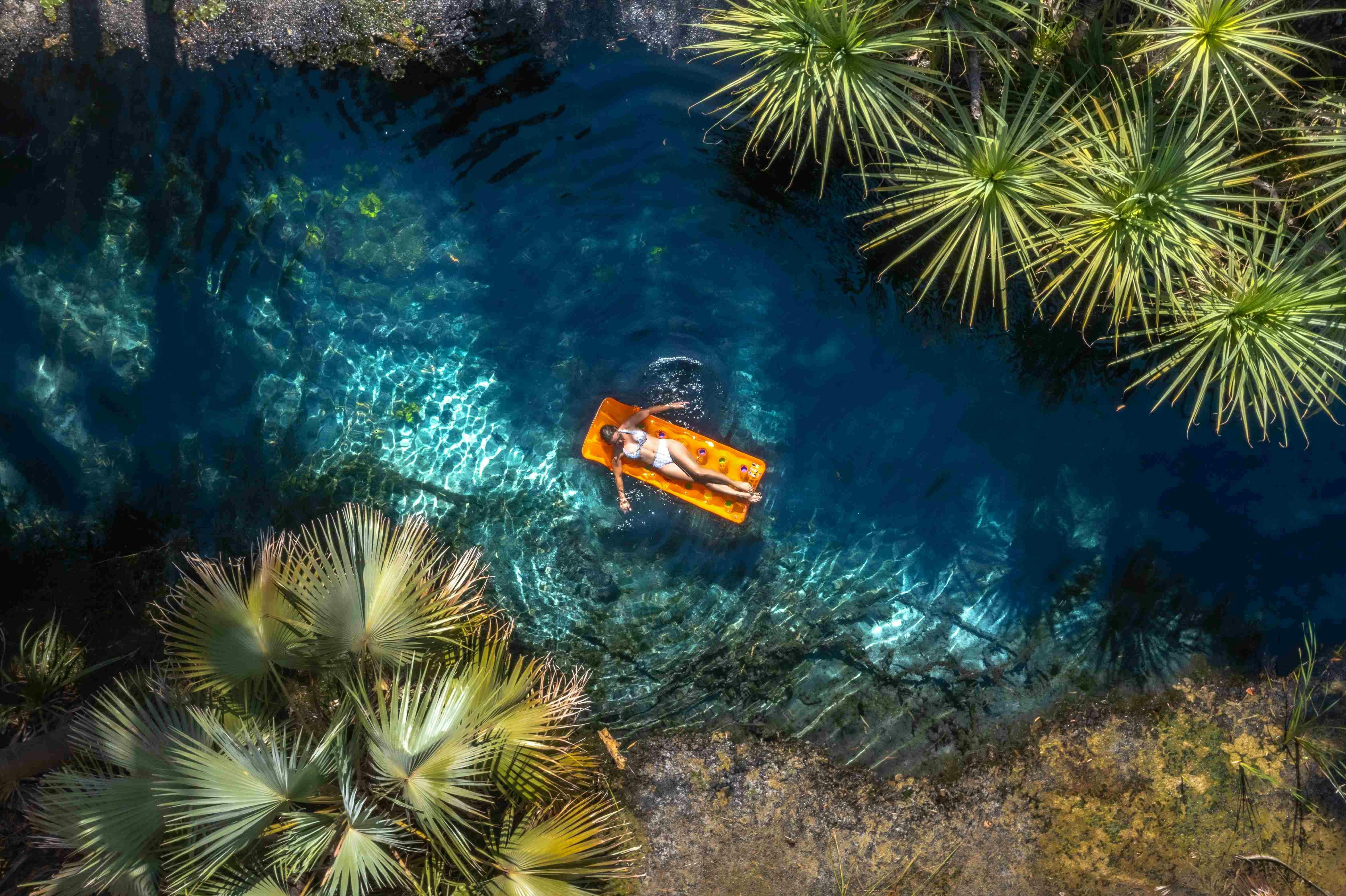 Aerial view of a woman floating on a inflatable in the Mataranka thermal pool