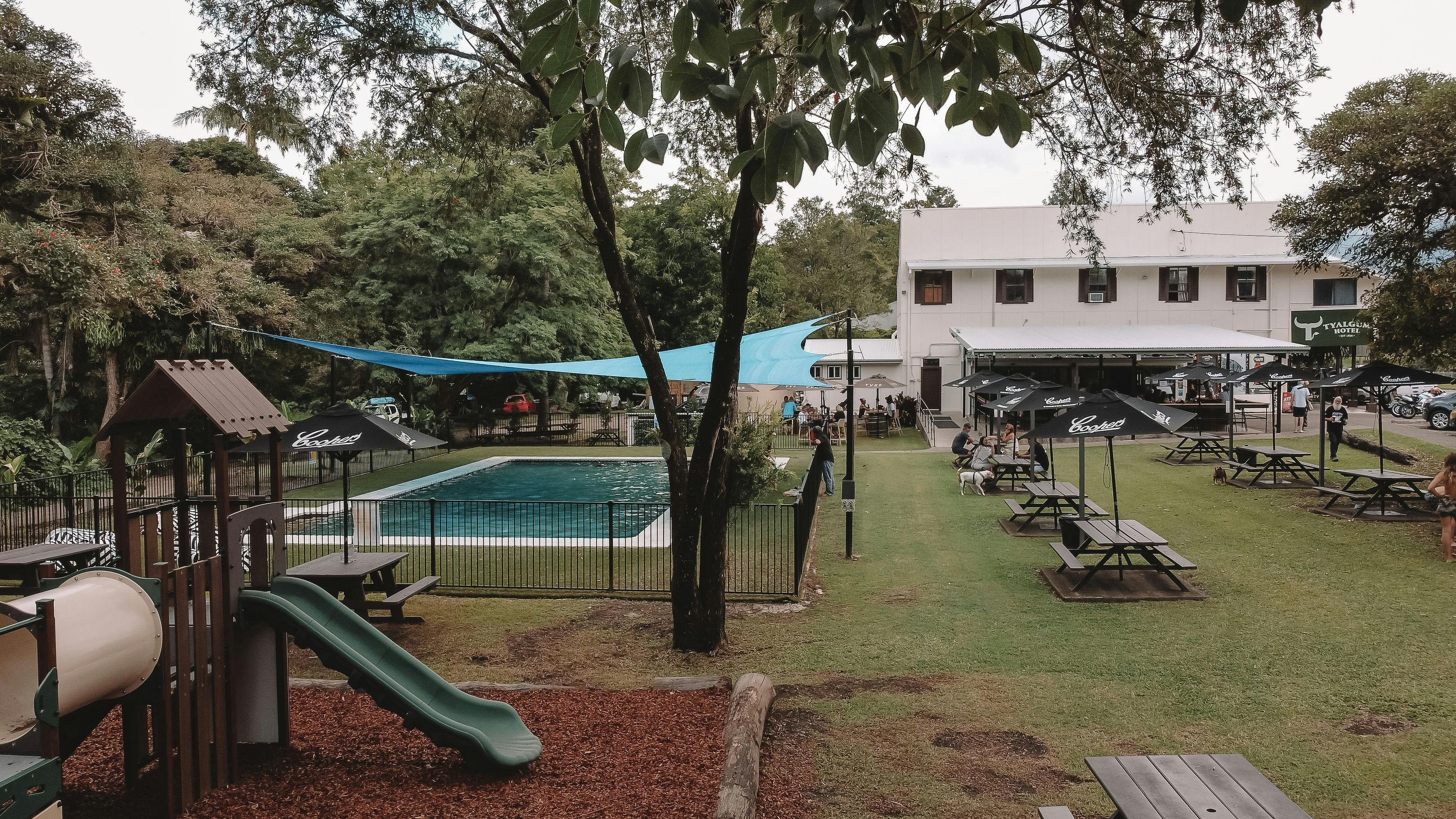 Garden area with children's playground and  Pool with trees and tables on grassed area