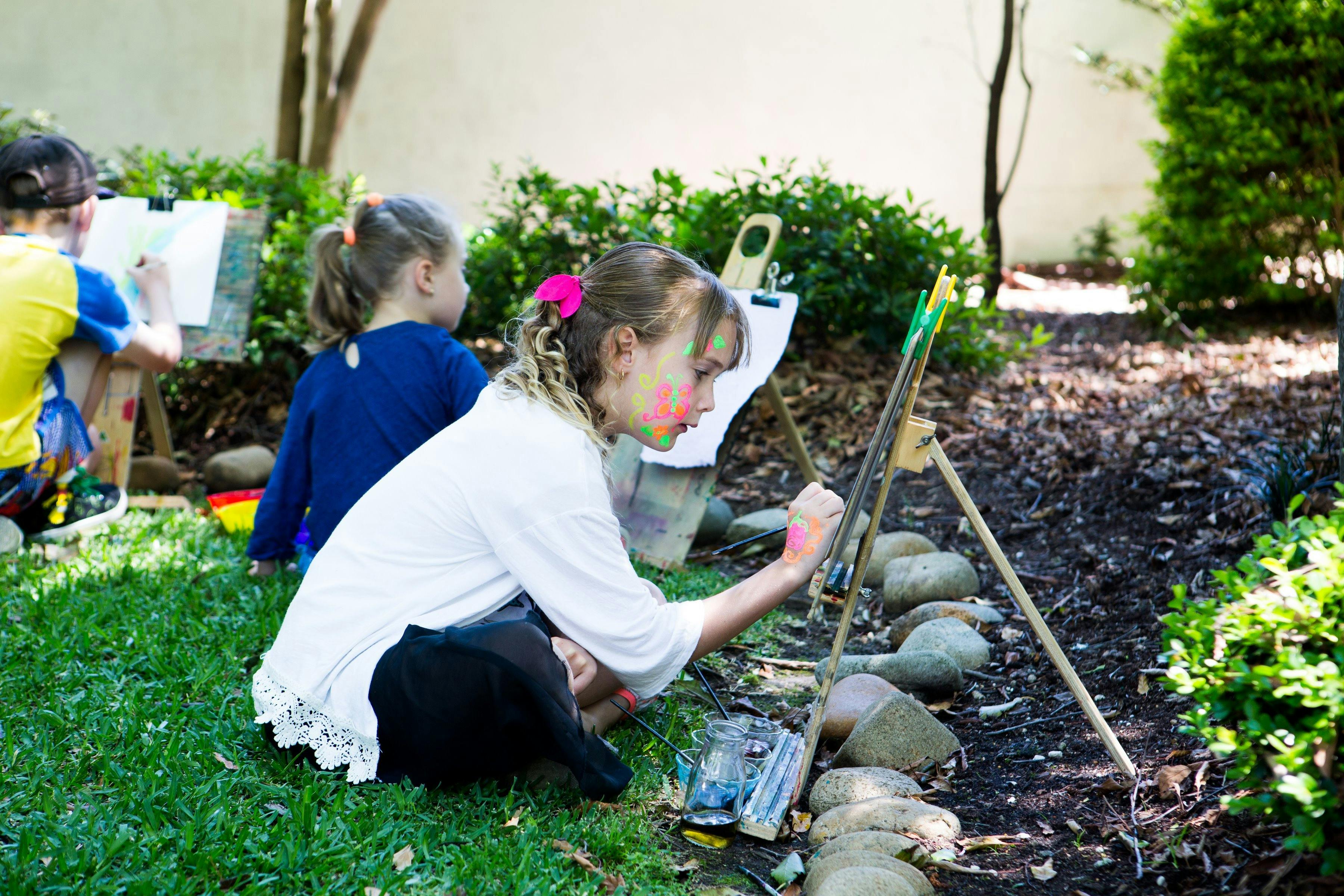日本庭園のイーゼルで絵を描く若い女の子