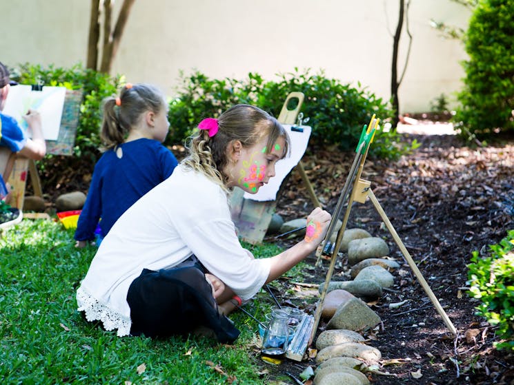 A young girl painting on an easel in the japanese garden
