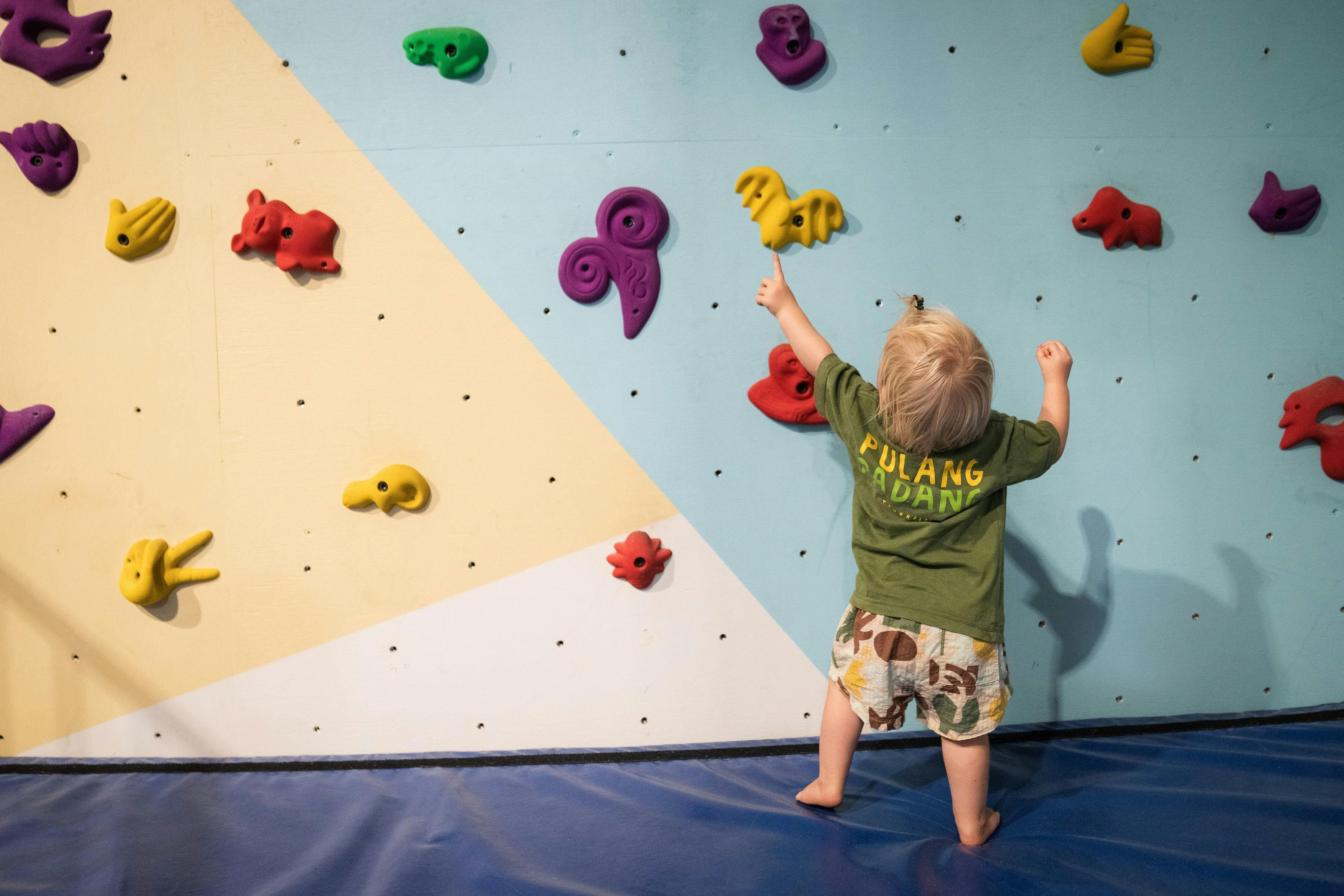 A toddler is attempting to climb on the kids wall