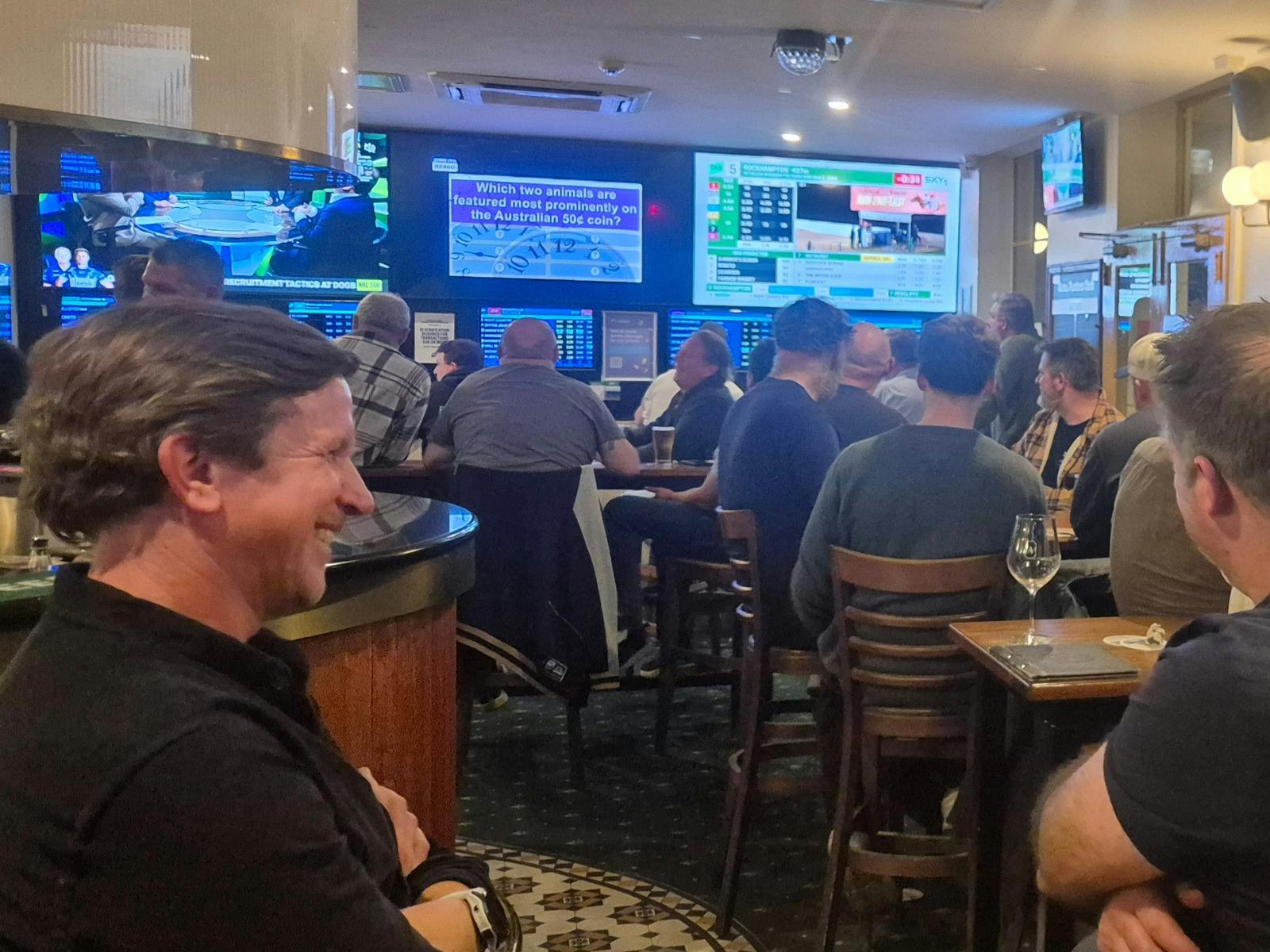 People sitting together laughing, eating and drinking and playing trivia