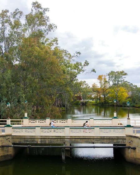 two cyclist ride over a heritage bridge that goes over the wollundry lagoon