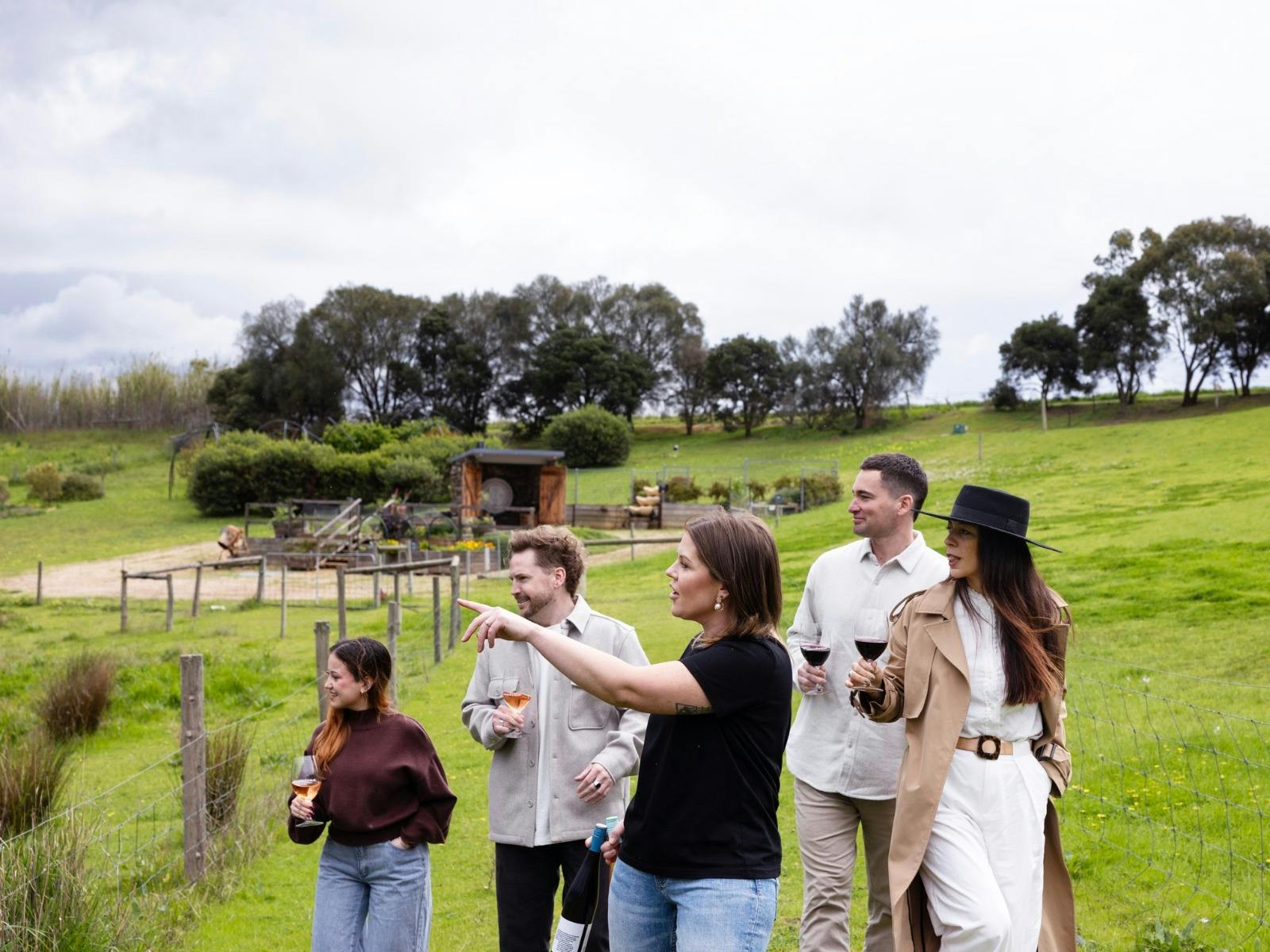 Gemtree staff member hosting 4 customers as they walk through the proprty holding glasses of wine