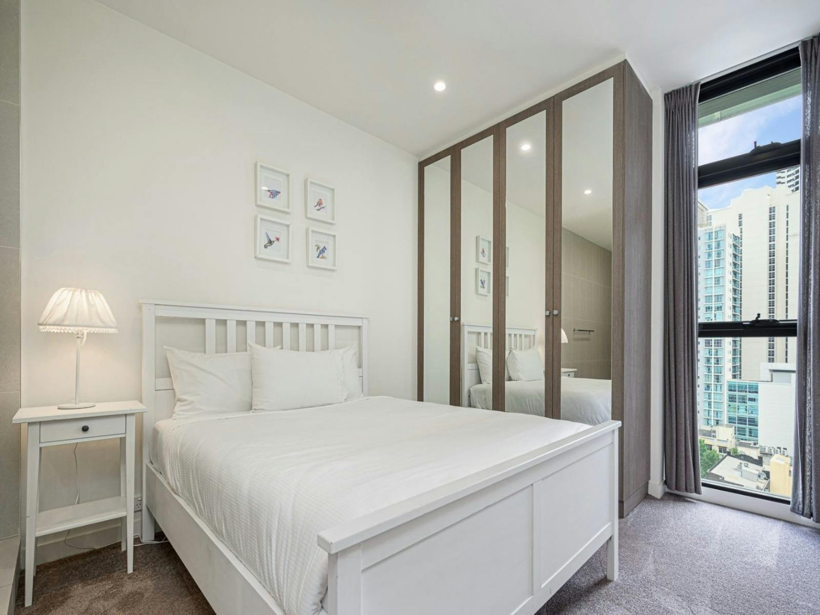Bedroom featuring a queen-size bed, bedside table, and built-in wardrobe.