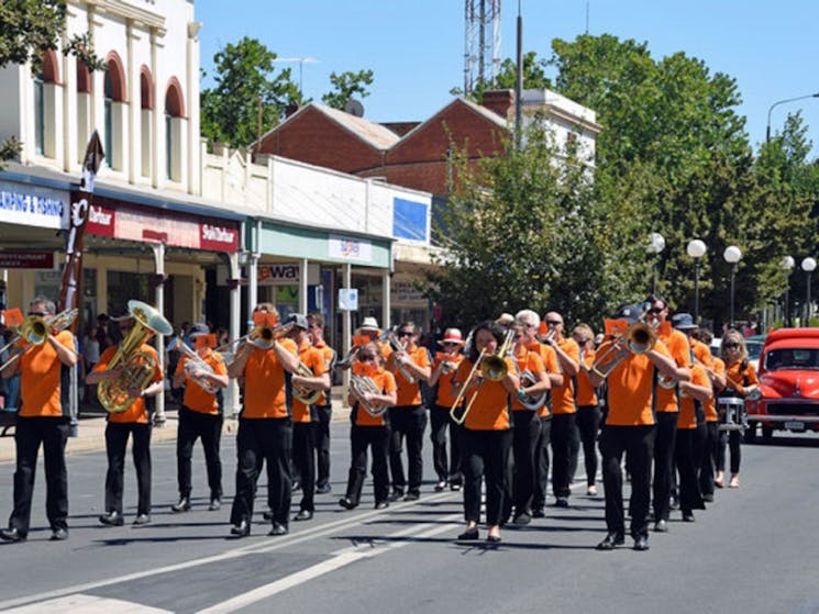 Brass band members dressed in orange shirts and black pants
