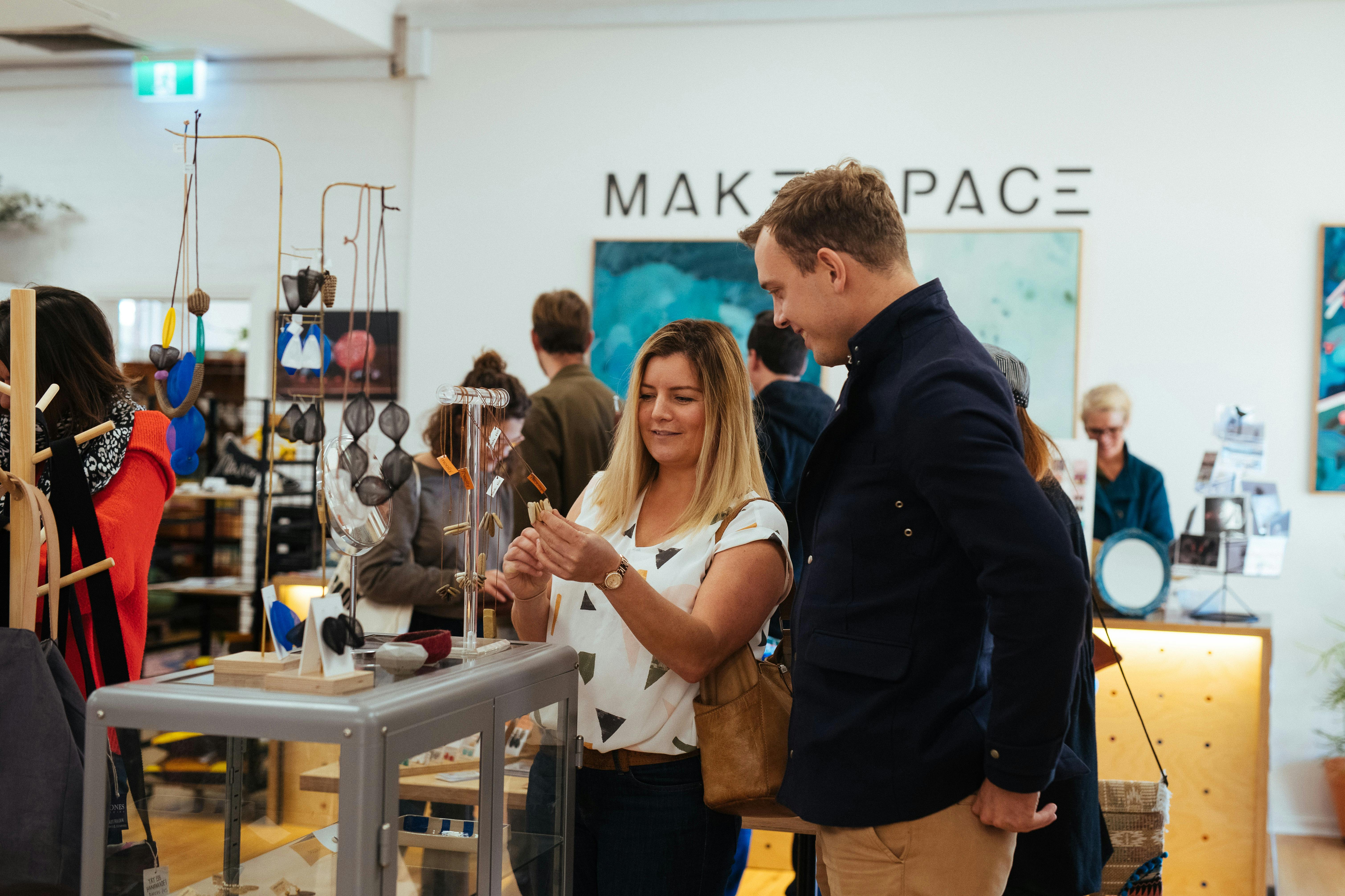 Two guests on a private walking tour of Newcastle looking at jewellery made by a local designer