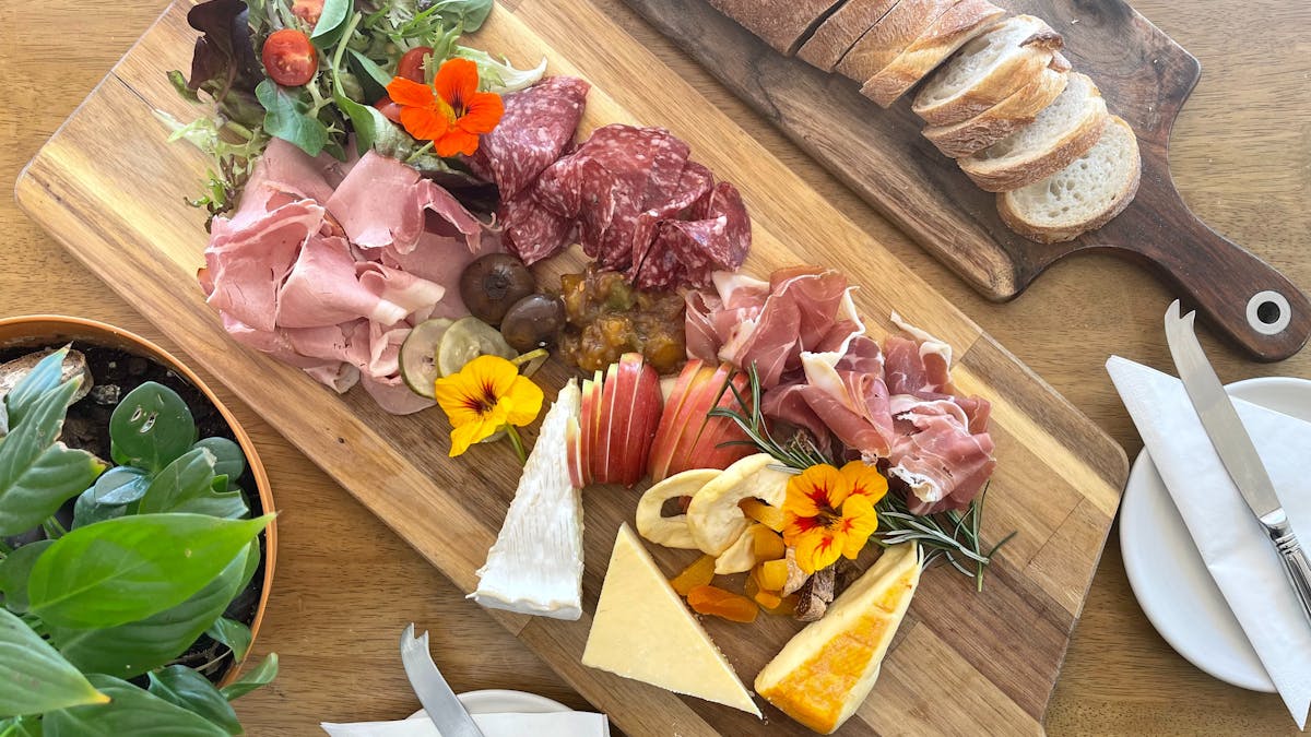 Ploughman's lunch laid on a board, including 3 local cheeses and 3 sets of cured meats.