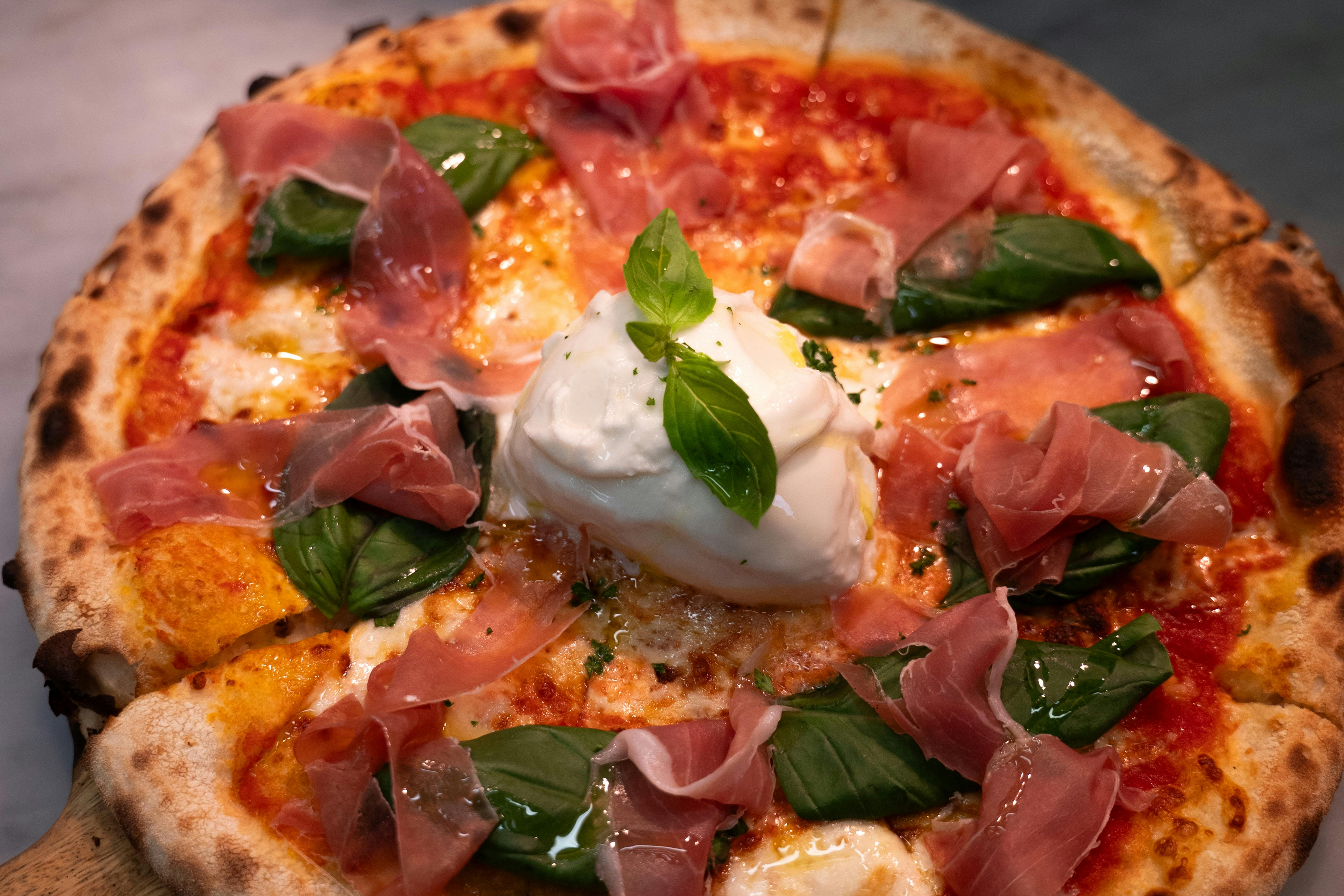 Pizza with prosciutto, creamy burrata and fresh basil at Fellini, Hobart waterfront.