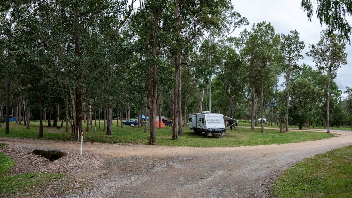 Open camping area with a caravan and tents. Open camping area with a caravan and tents.